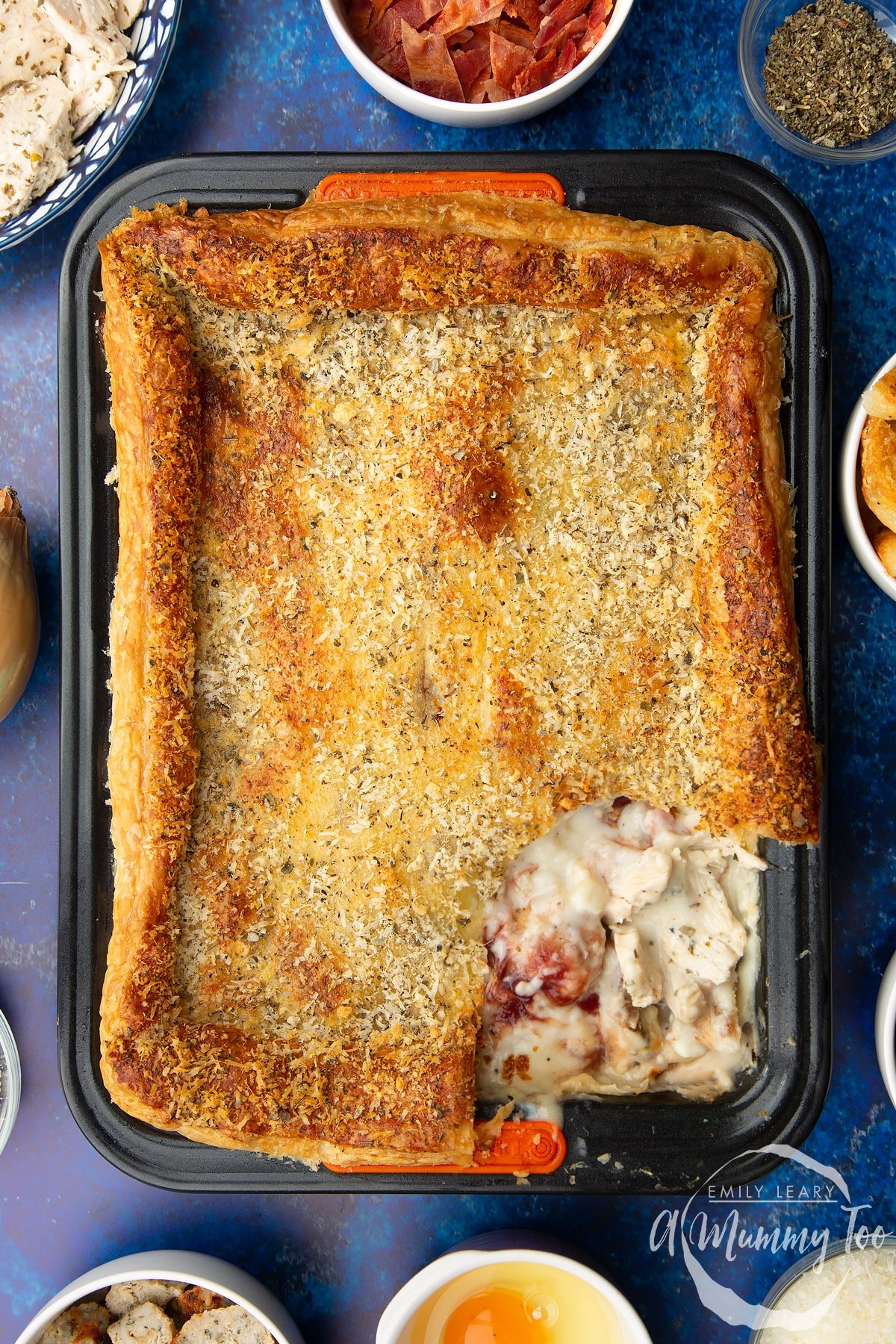 A tray of cooked leftover Christmas dinner pie. A piece of the puff pastry lid has been taken away to reveal the creamy filling.