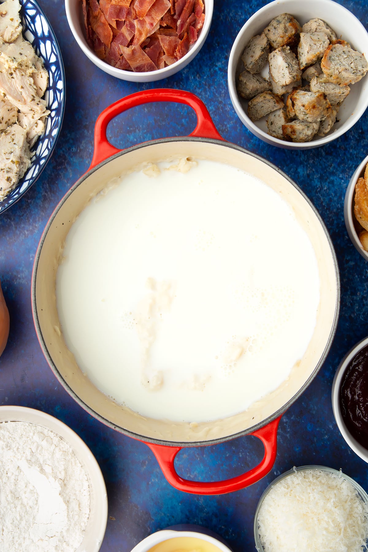 Fried onions in a milk sauce in a pan. Ingredients to make a leftover Christmas dinner pie surround the pan.