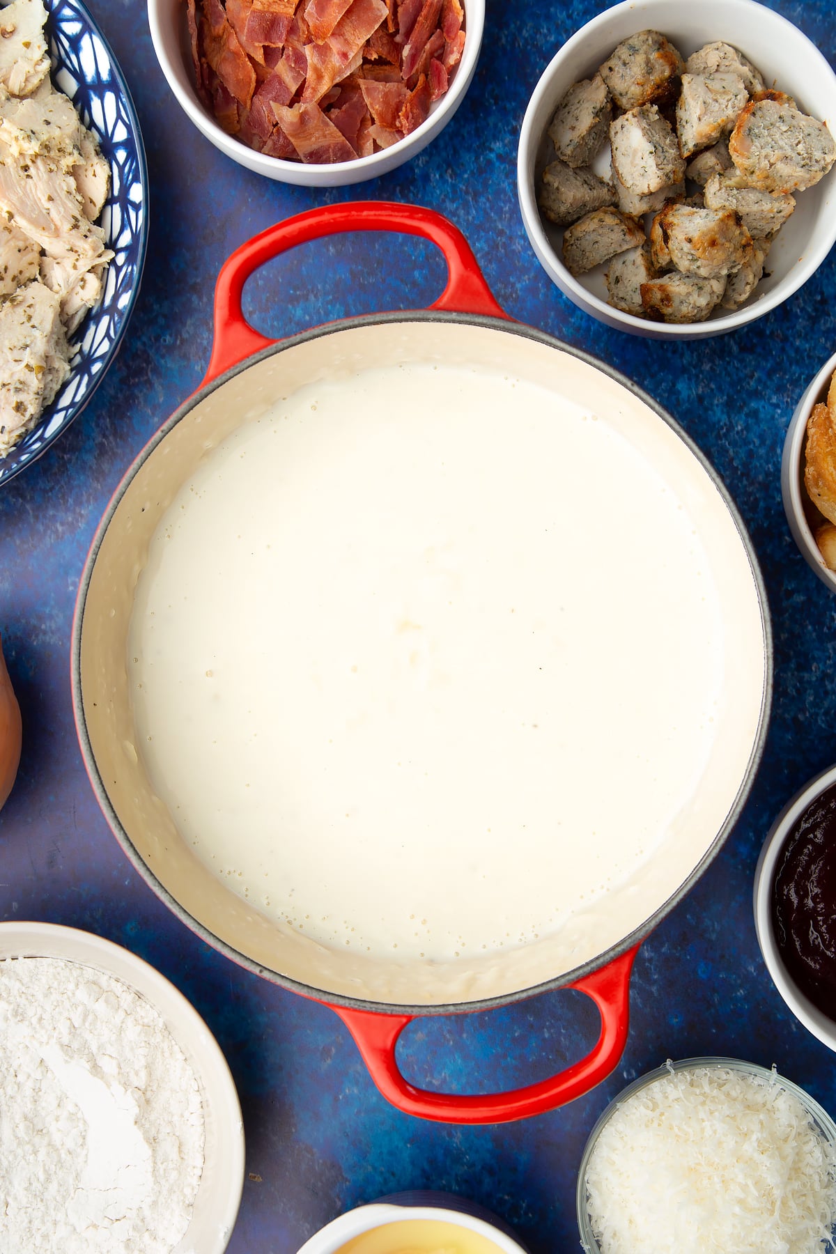 White onion sauce in a pan. Ingredients to make a leftover Christmas dinner pie surround the pan.