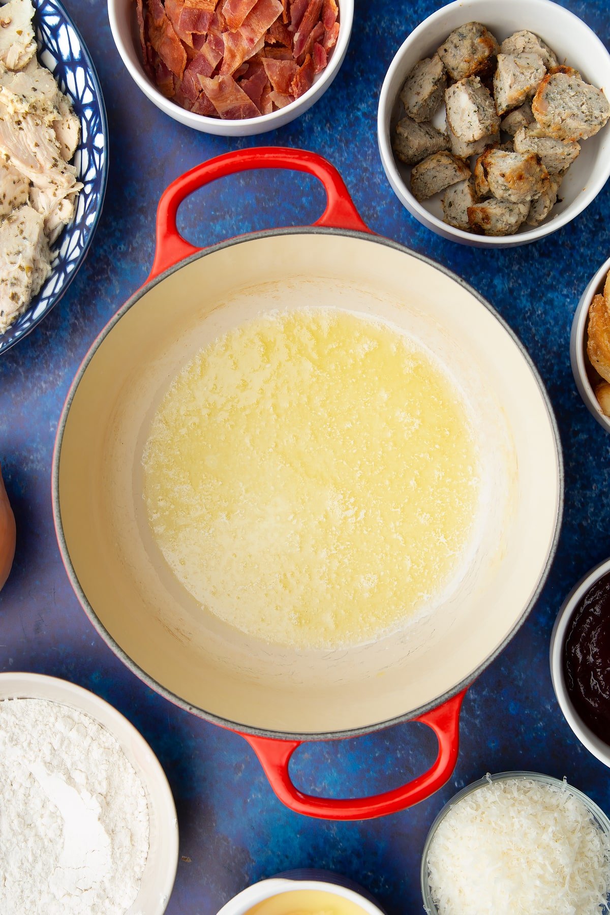 Melted butter and oil in a pan. Ingredients to make a leftover Christmas dinner pie surround the pan.