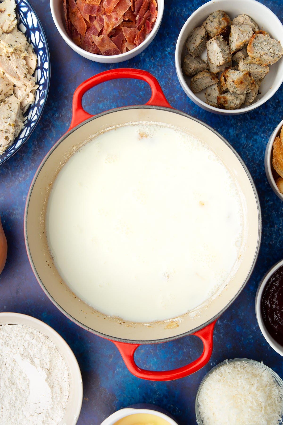 Fried onions and milk in a pan. Ingredients to make a leftover Christmas dinner pie surround the pan.