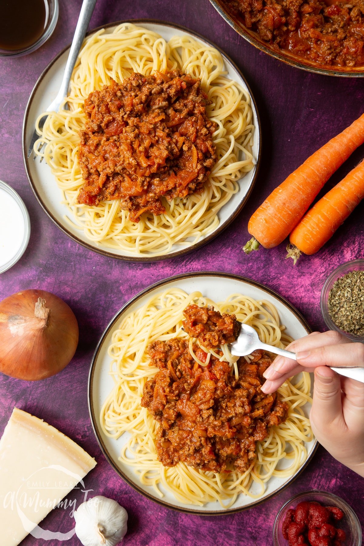 Spaghetti bolognese Gordon Ramsay style served on plates. A fork lifts spaghetti from the plate.