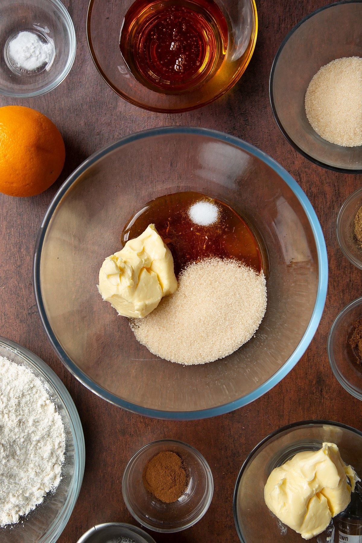 Butter, sugar, salt and golden syrup in a bowl. Ingredients to make autumn cookies surround the bowl.