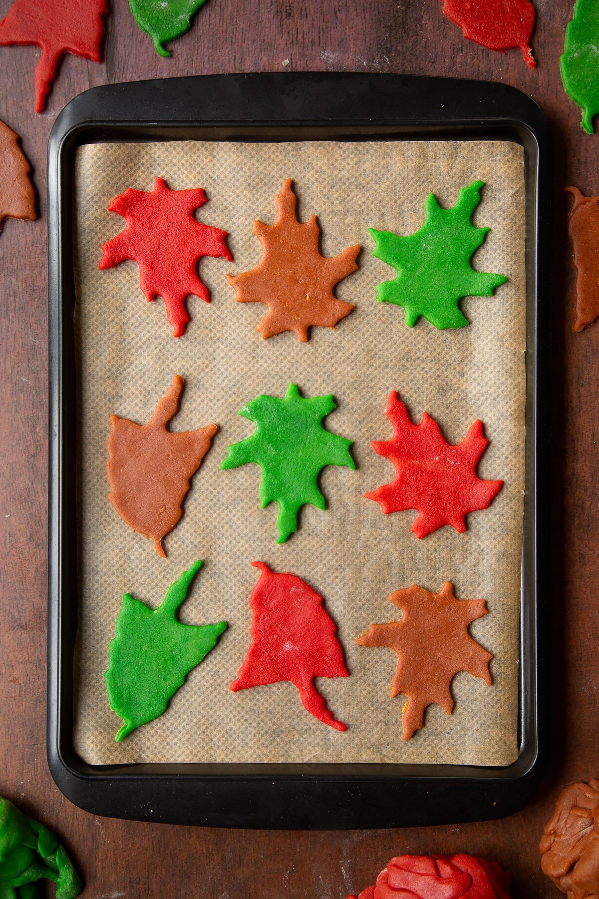 Autumn leaf cookies ready to bake on a tray lined with baking paper.