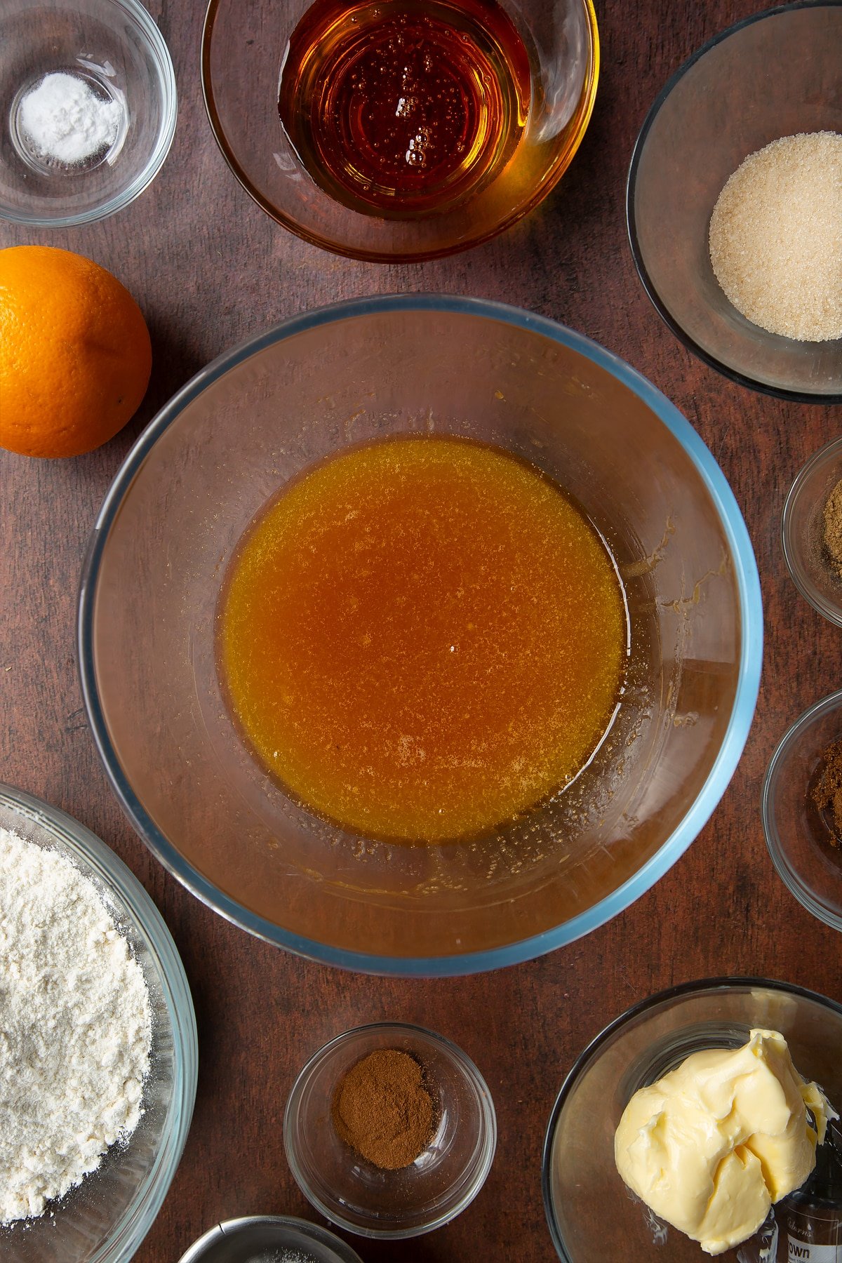 Melted butter, sugar and golden syrup in a bowl. Ingredients to make autumn cookies surround the bowl.