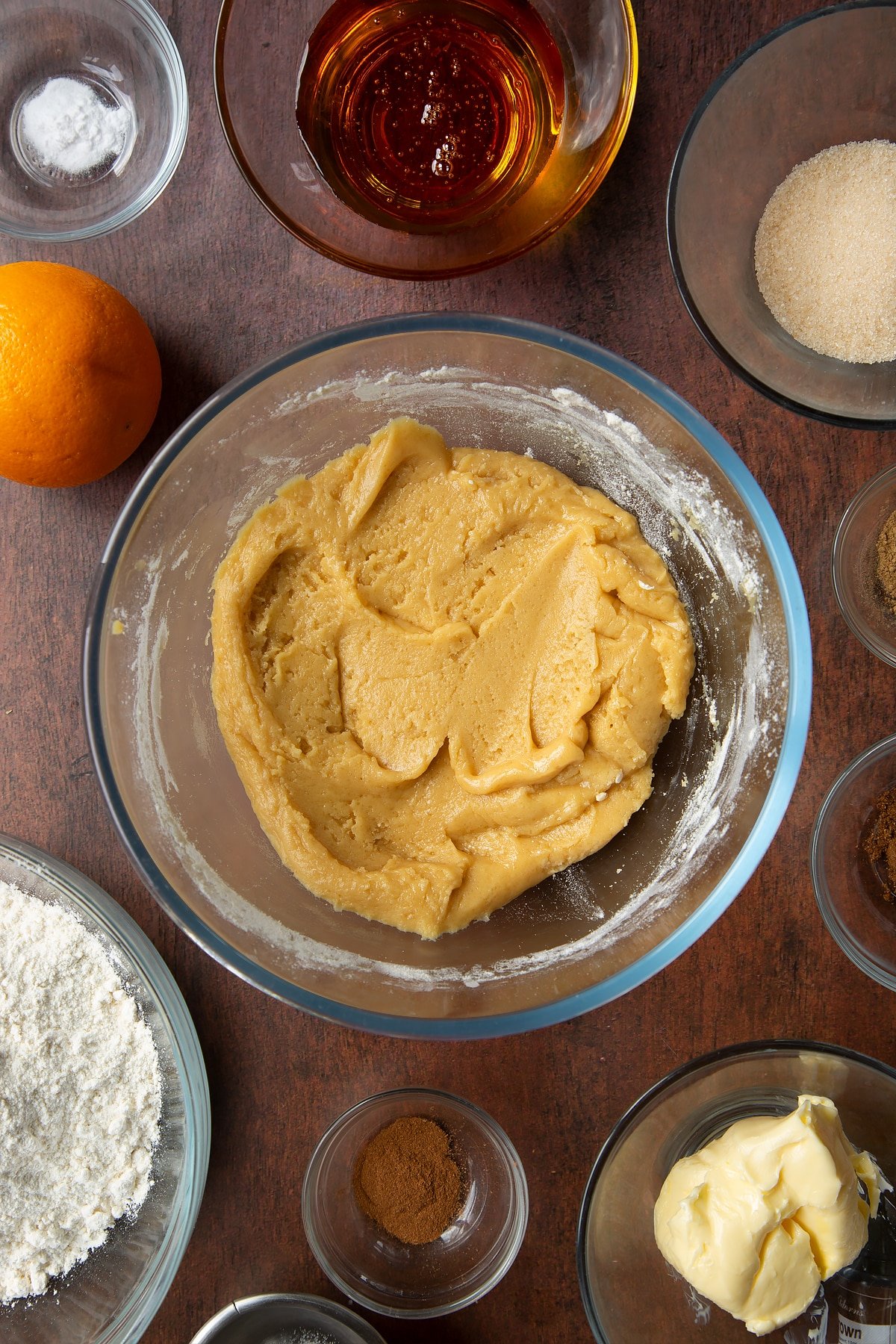 Cookie dough in a bowl. Ingredients to make autumn cookies surround the bowl.