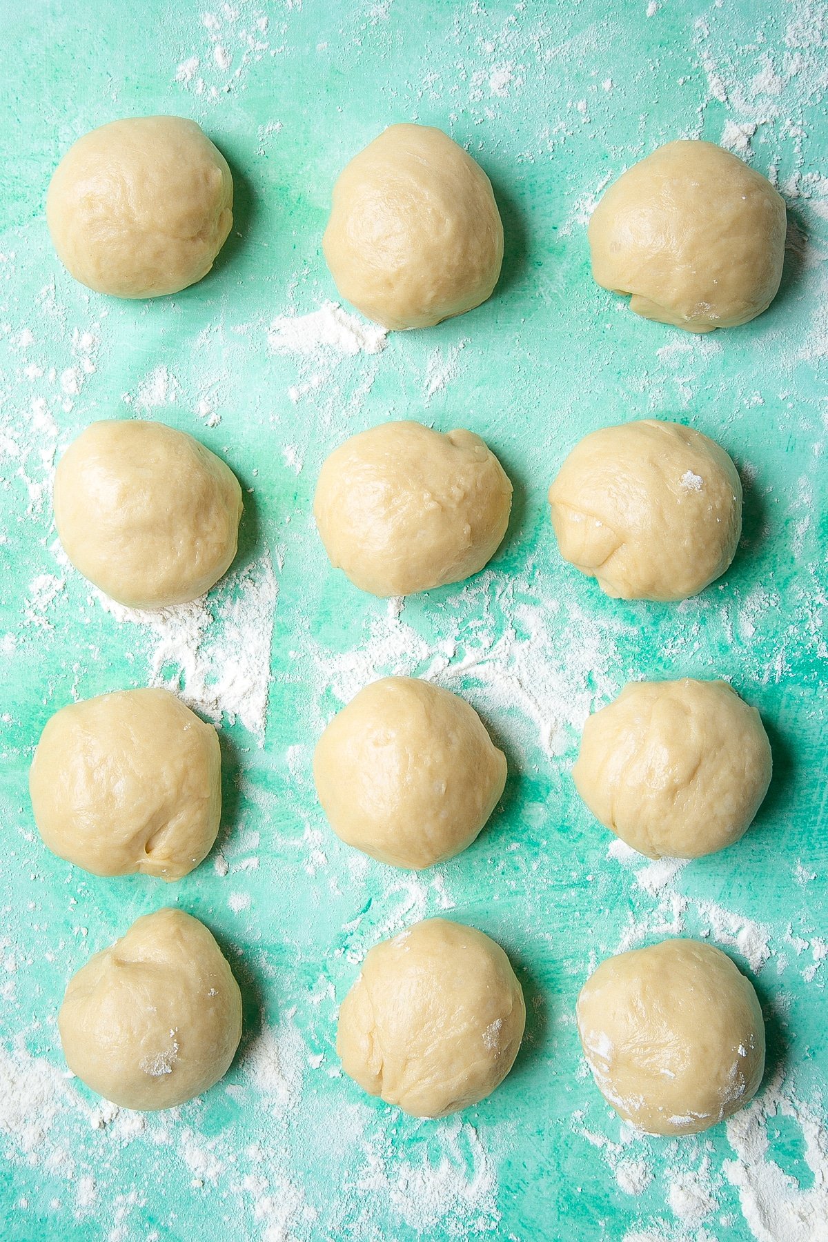 Bread dough rolled into 12 balls on a floured surface.