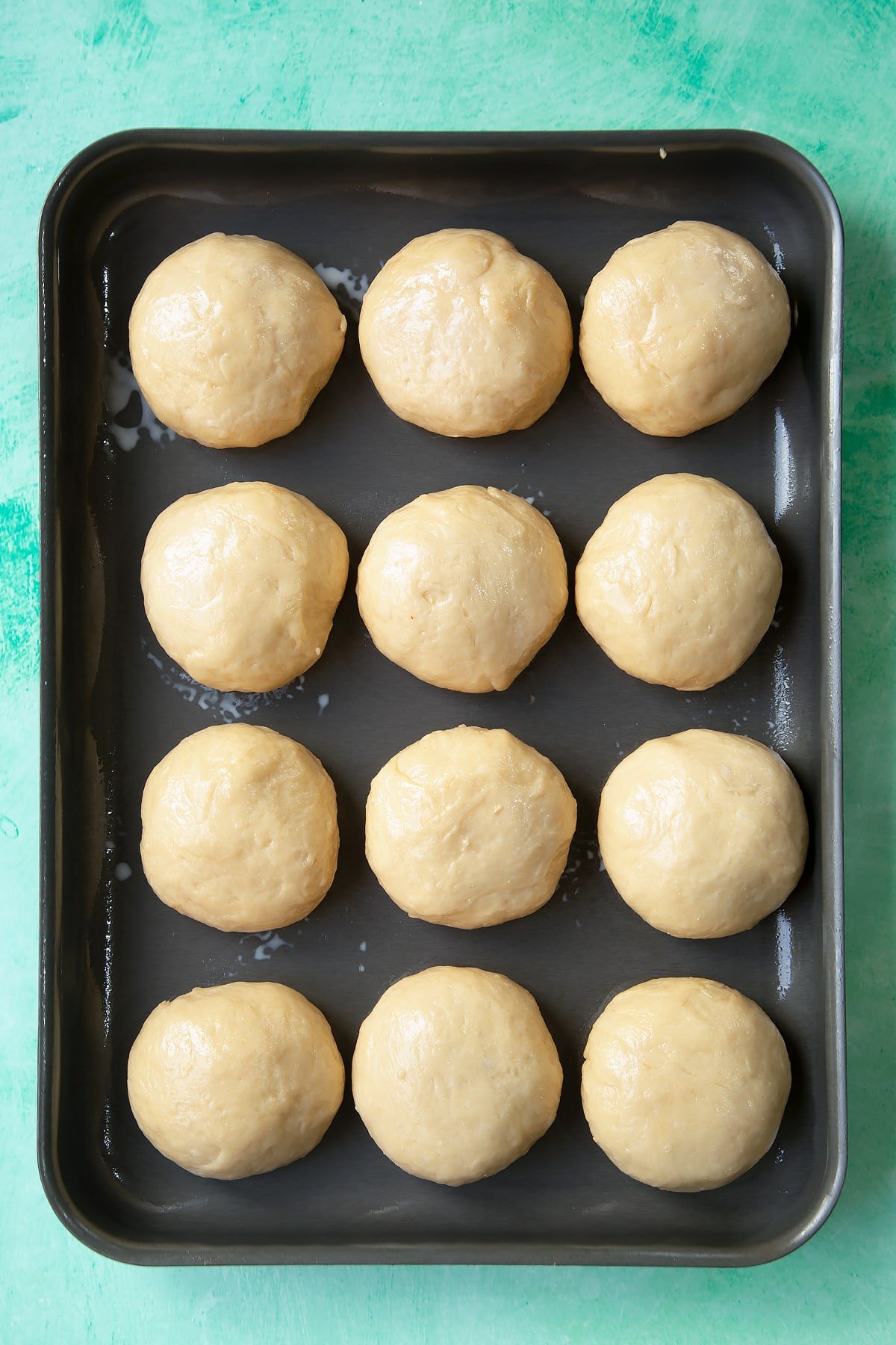 Freshly formed balls of doughy chicken doughnuts turned upside down on a tray.