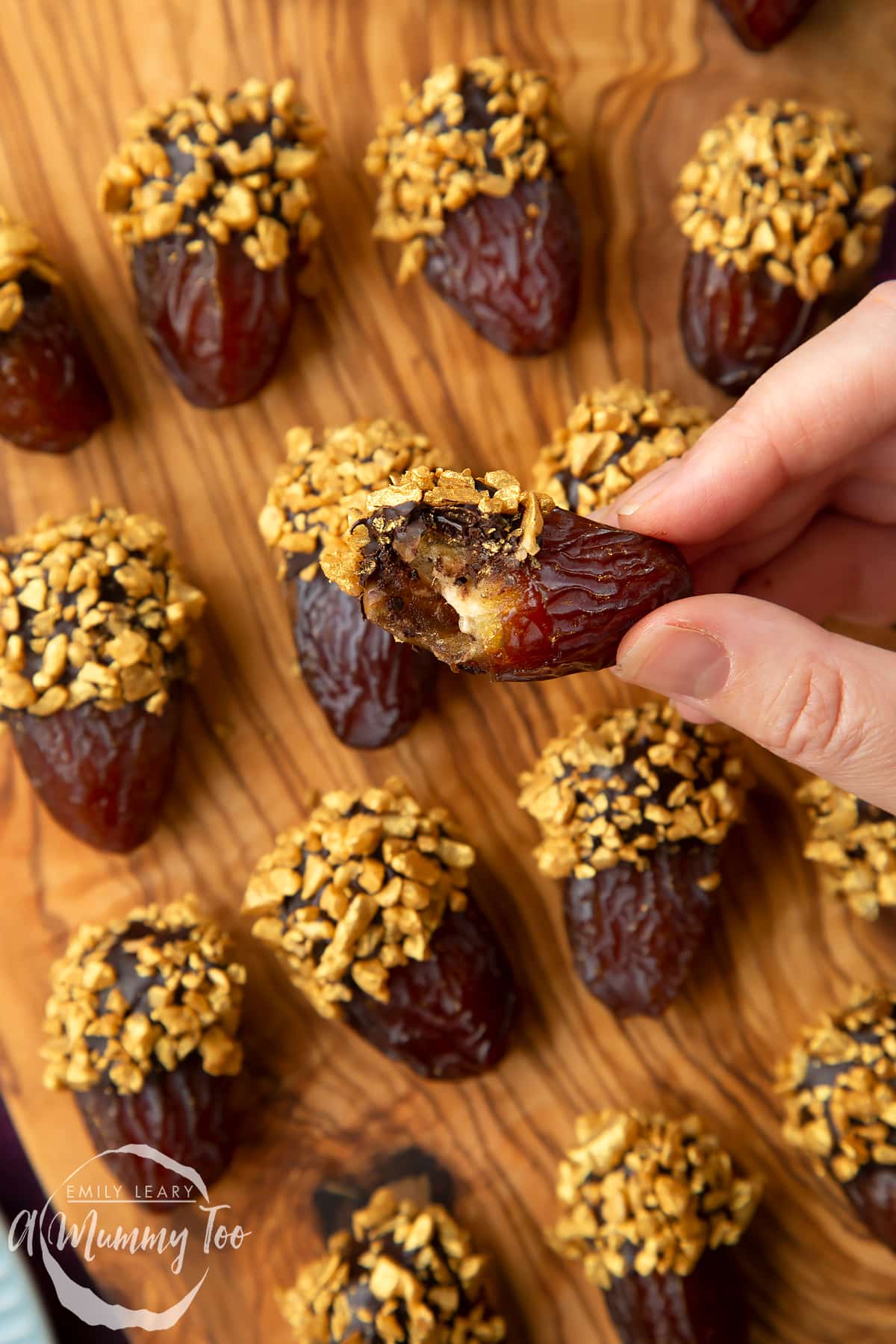 A hand holding a chocolate date that had been bitten into. 