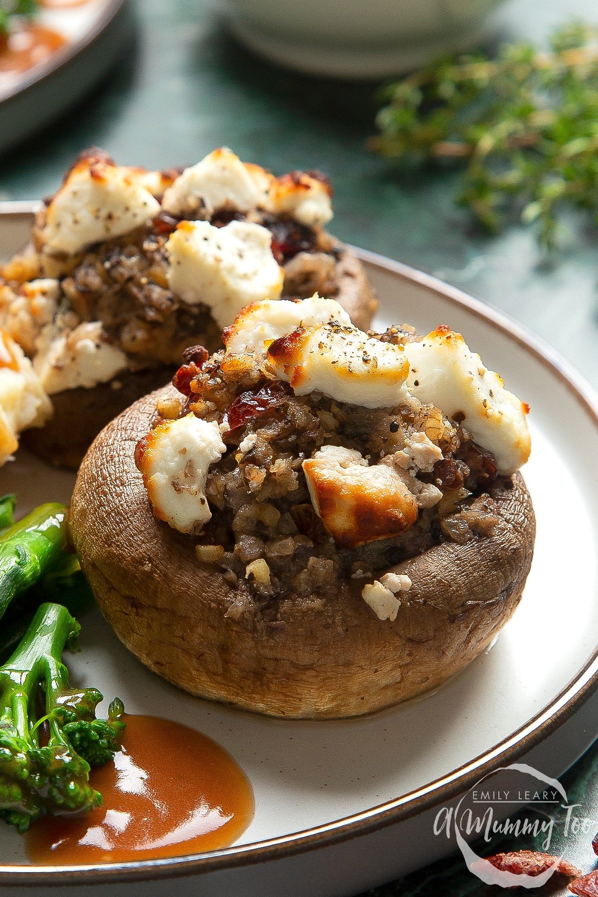 Front angle shot of festive stuffed mushrooms recipe served on a white platewith a mummy too logo in the lower-right corner