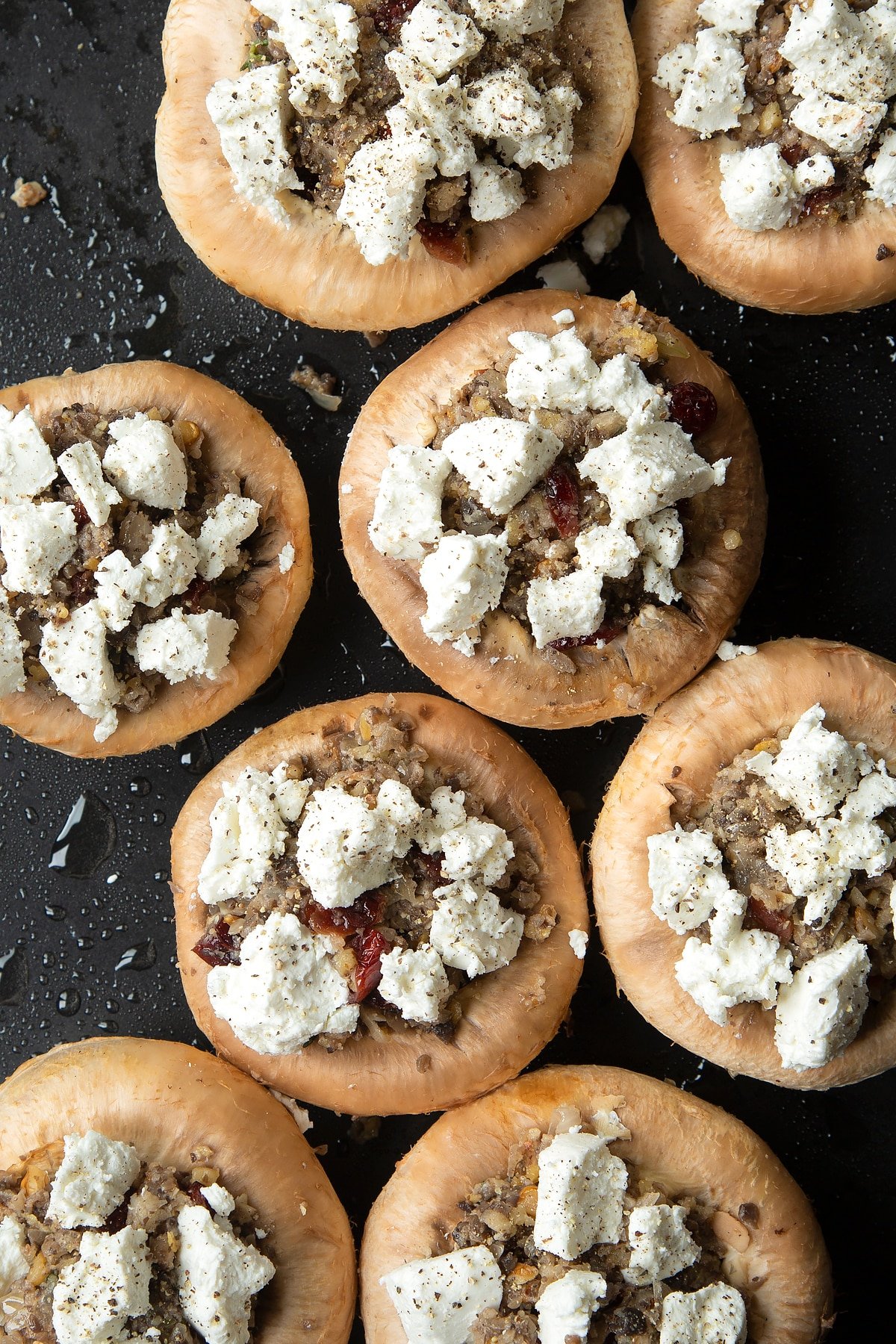 Overhead shot of stuffed mushrooms drizzled with oil on a baking tray