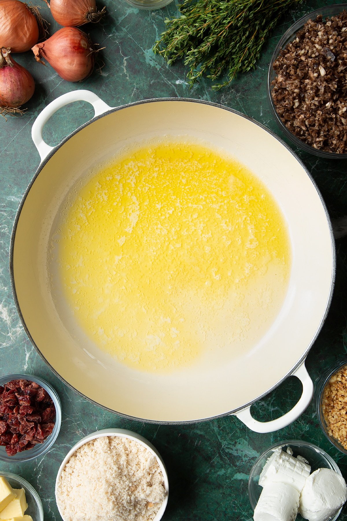 Overhead shot of melted butter cubes and oil in a large frying pan