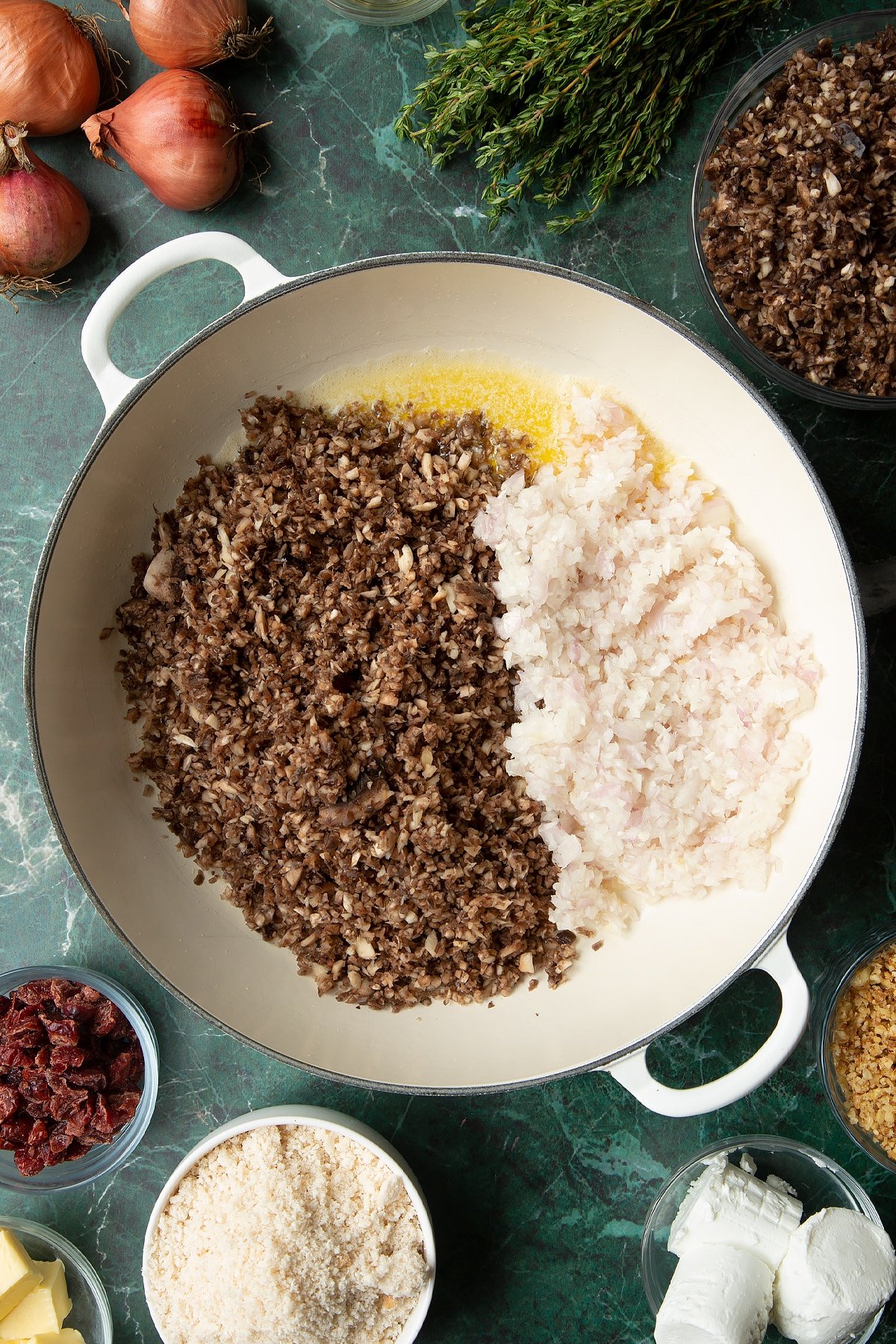 Overhead shot of finely chopped mushrooms and shallots in a large frying pan