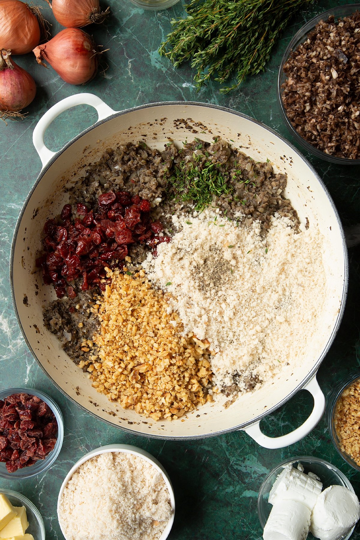 Overhead shot of cranberries, cooked mushrooms, walnuts, thyme, and breadcrumbs in a large frying pan