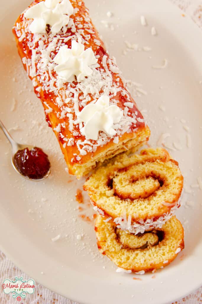 Mexican jelly roll overhead shot with one slice cut off and a spoon full of jelly at the side.
