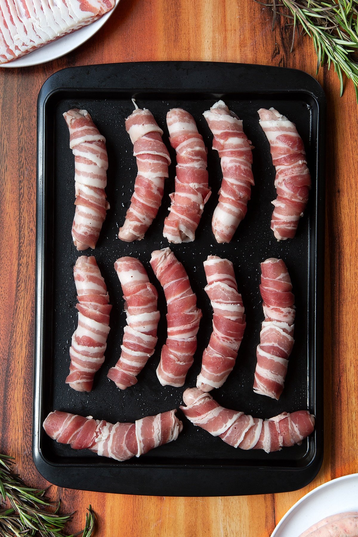 Overhead shot of bacon-wrapped sausages in black tray