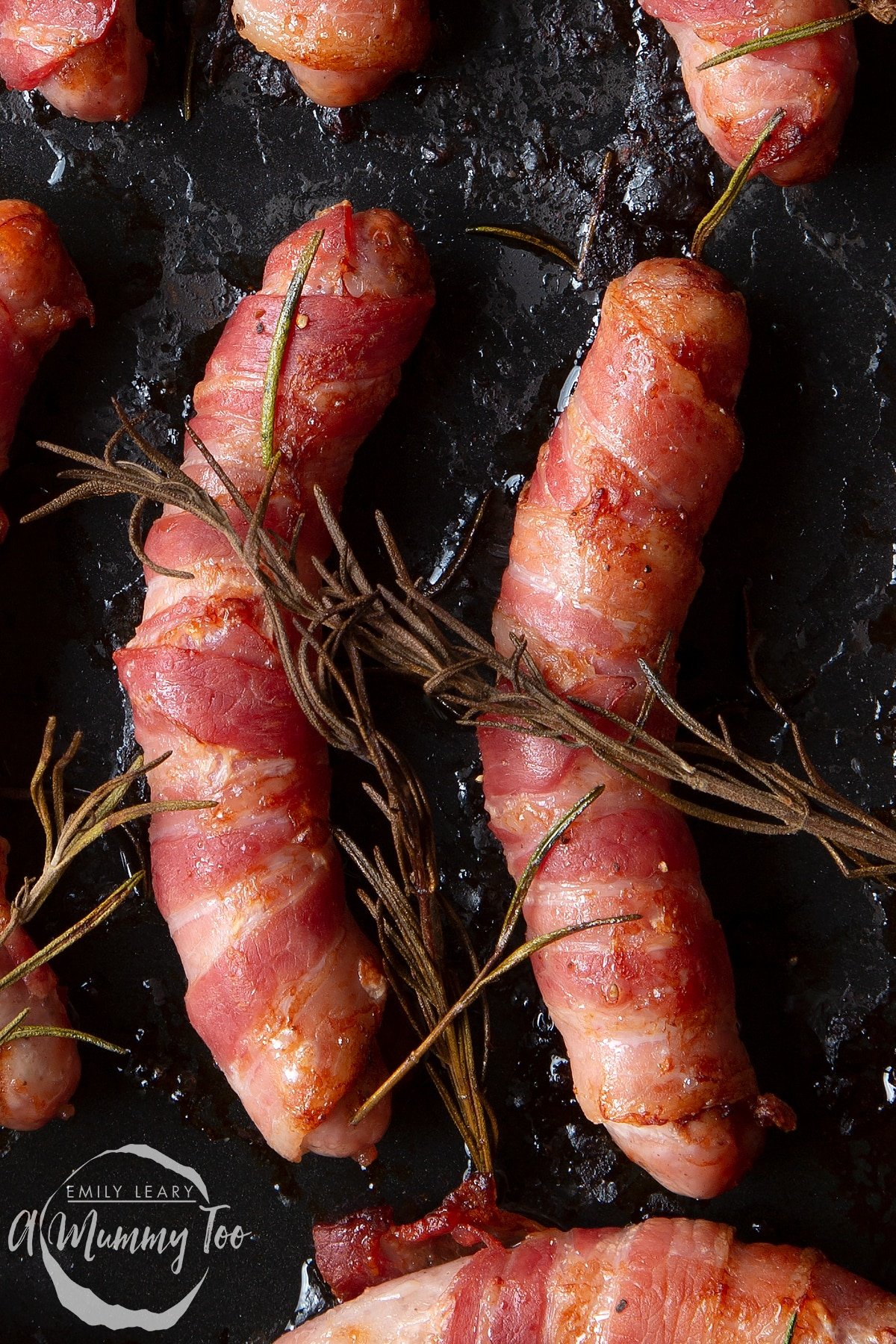 Front angle shot of Bacon with pigs in a blanket with rosemary with a mummy too logo in the lower-left corner