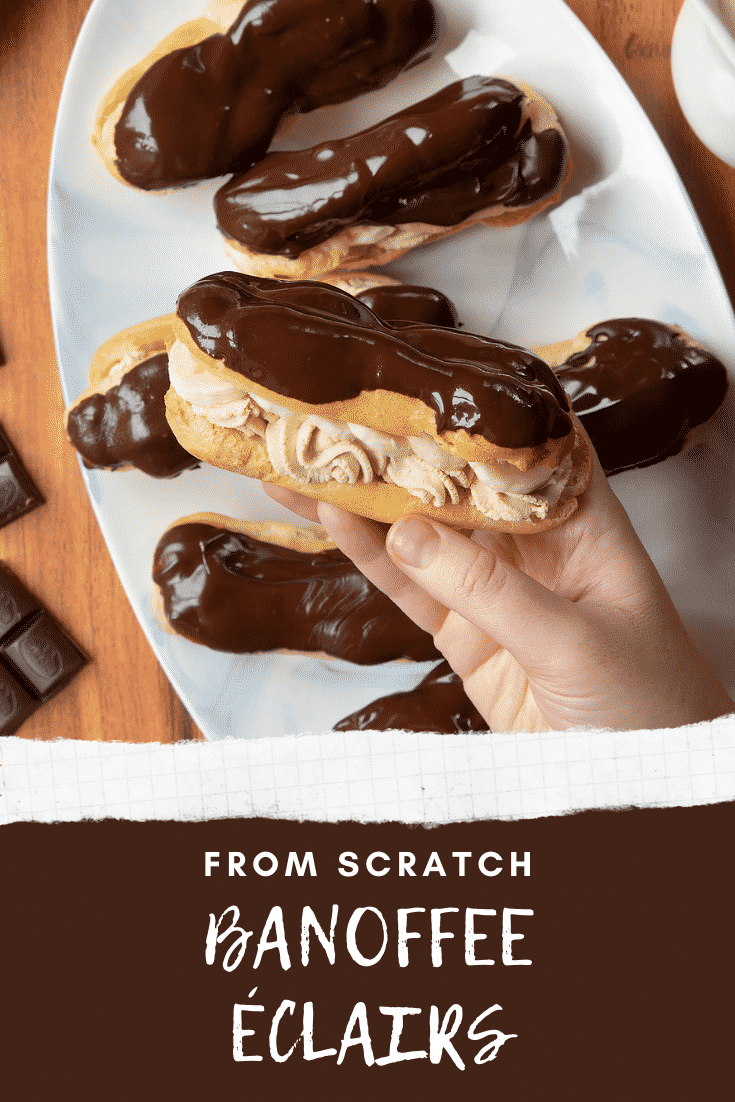 Overhead shot of the finished banoffee eclairs with one hand holding one of the eclairs closest to the camera. 