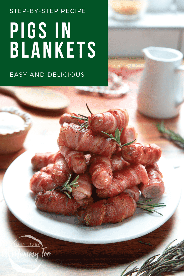 Forward shot of the pigs in blankets stacked on top of one and other on a white plate with some white text on a green background at the top of the image describing it for Pinterest.