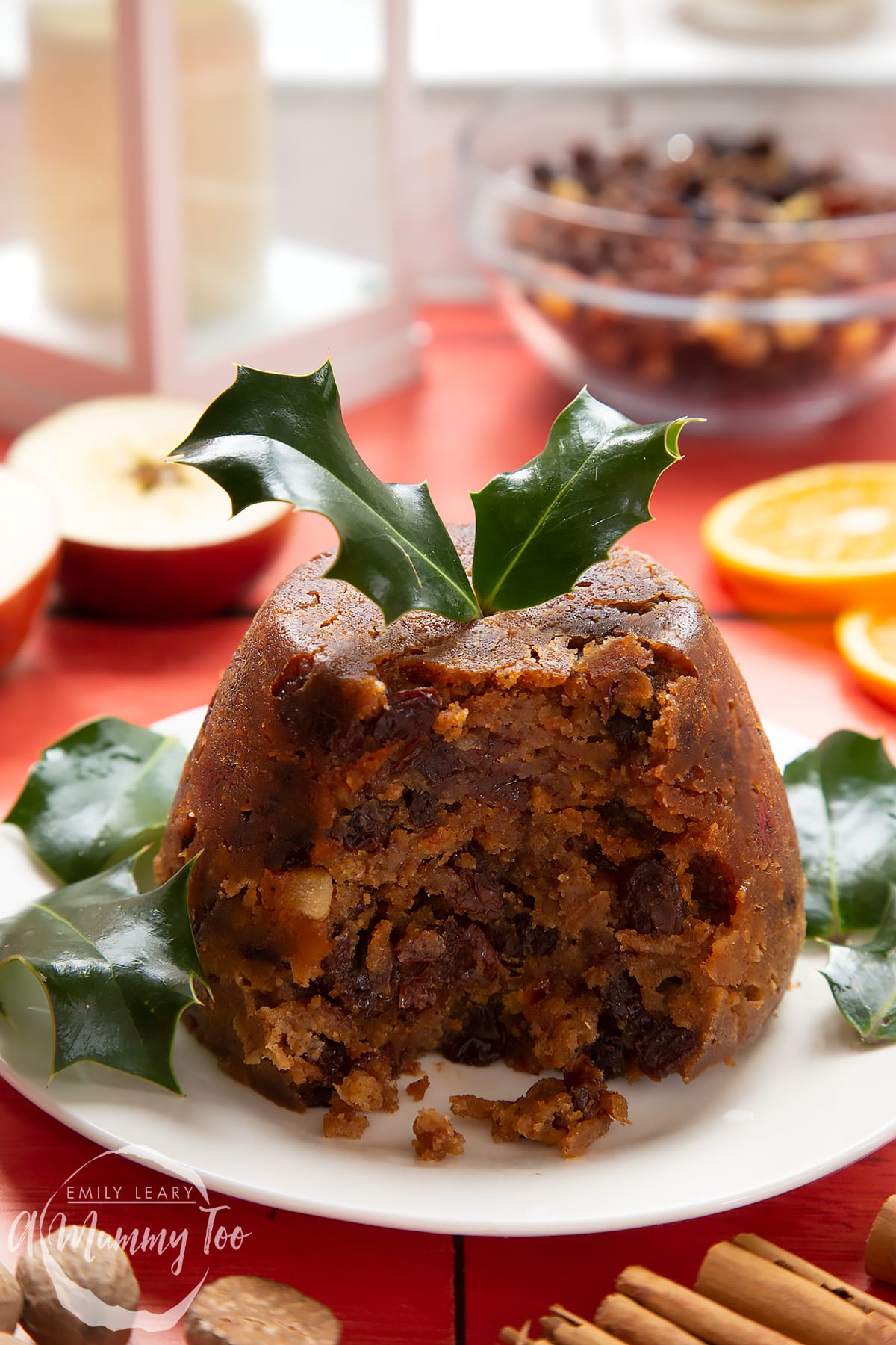 Front angle shot of half eaten Alcohol-free Christmas pudding served on a white plate with a mummy too logo in the lower-left corner