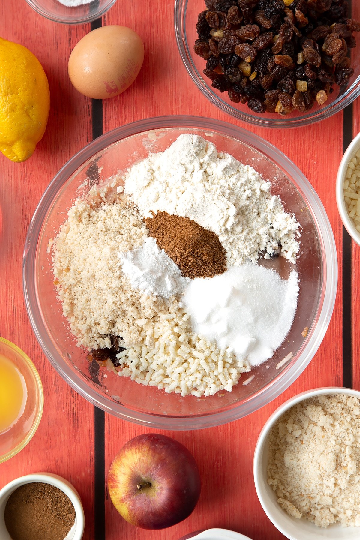 Overhead shot of mixed fruit, flour, sugar, suet, breadcrumbs, mixed spice, nutmeg, cinnamon and baking powder in a large mixing bowl