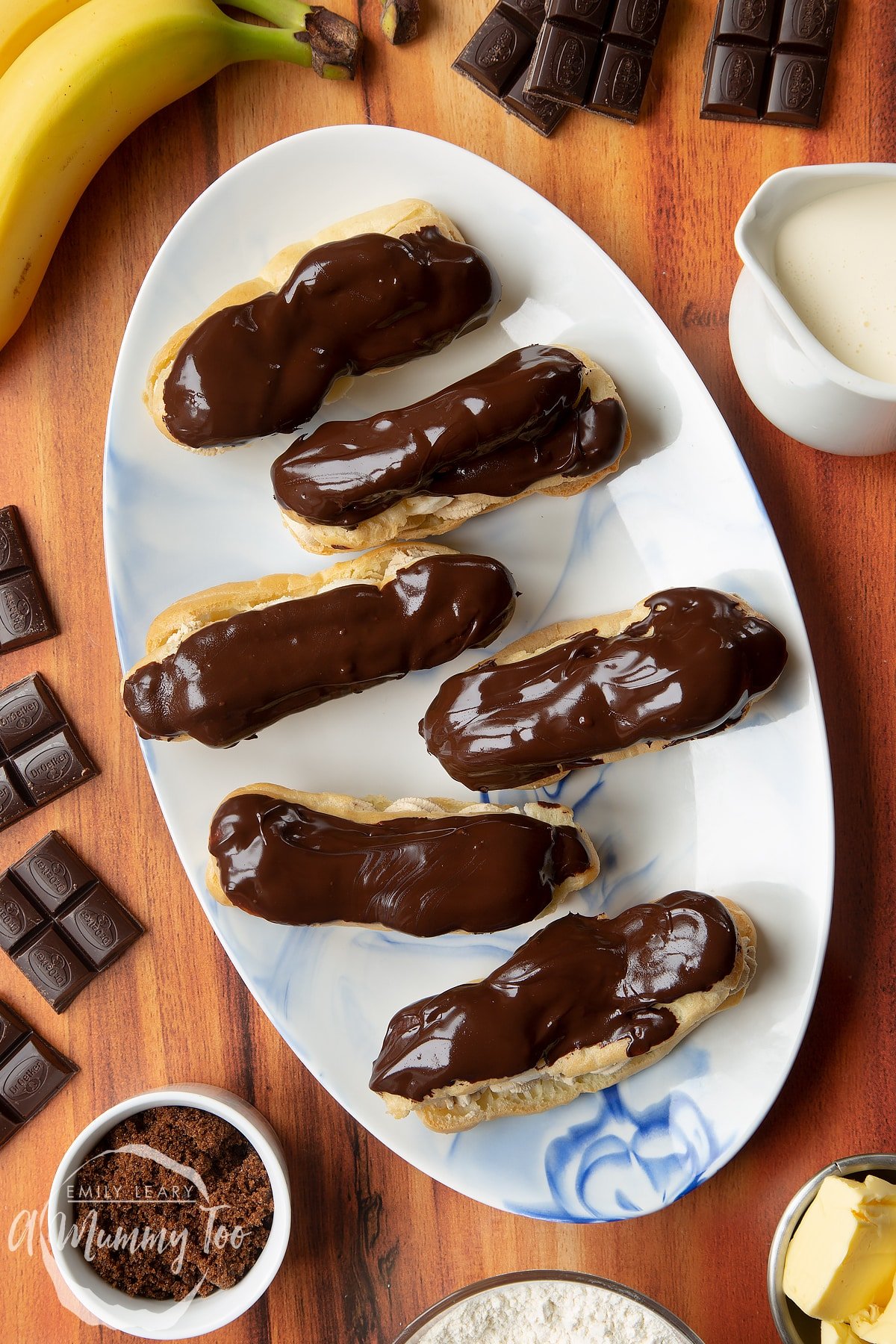 Overhead shot of eclair halves with slices of fresh banana on top served on a white plate
