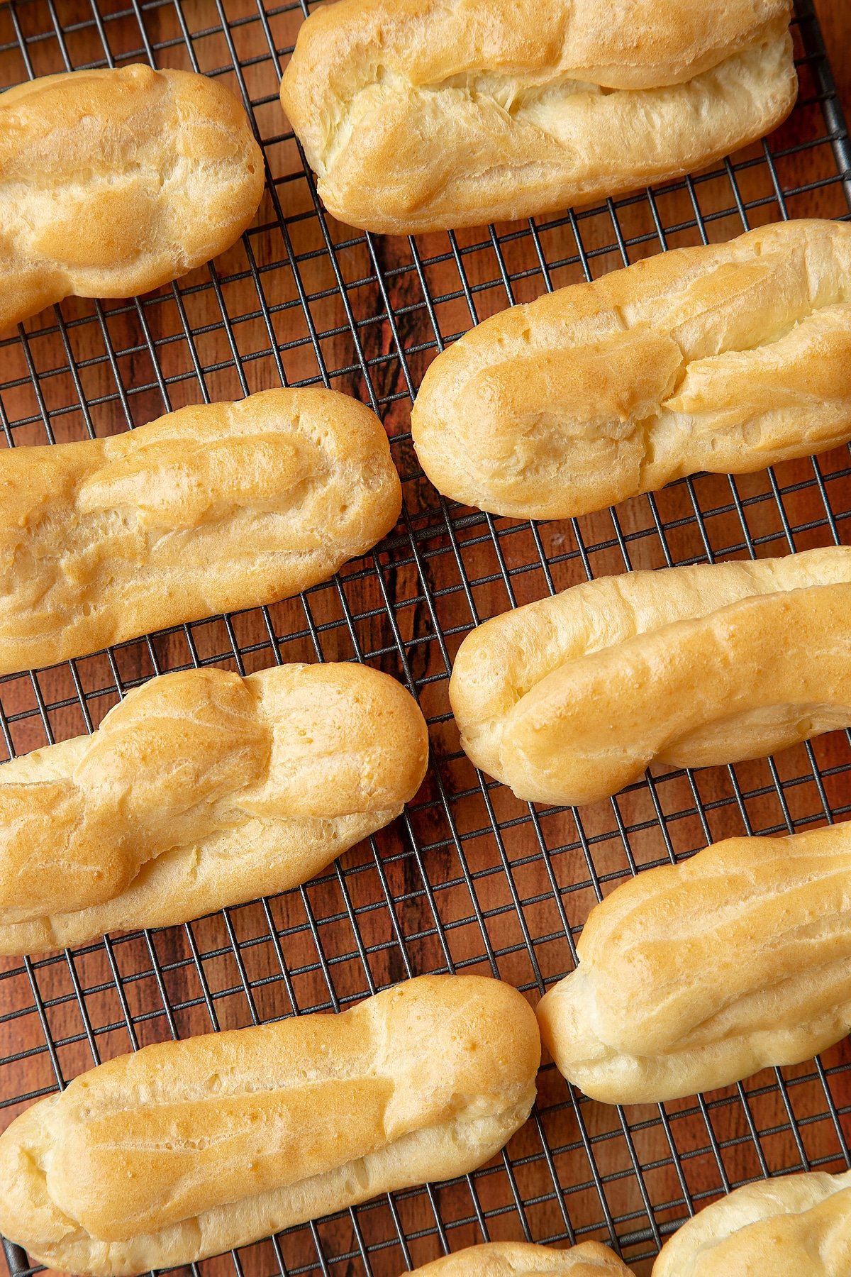 Close up overhead shot of baked choux pastry on a cooling wire rack. 