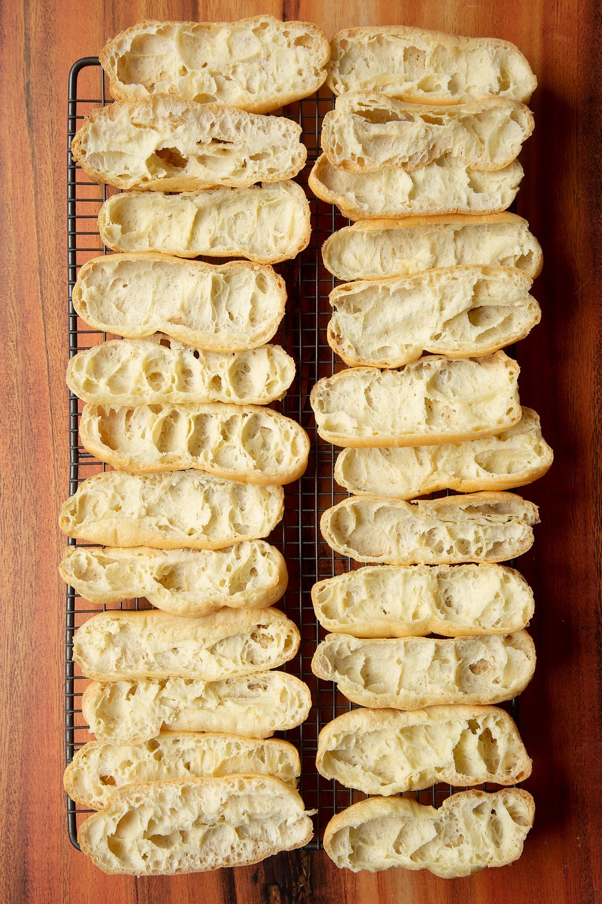 Baked choux pastry cut in half on a cooling wire rack. 