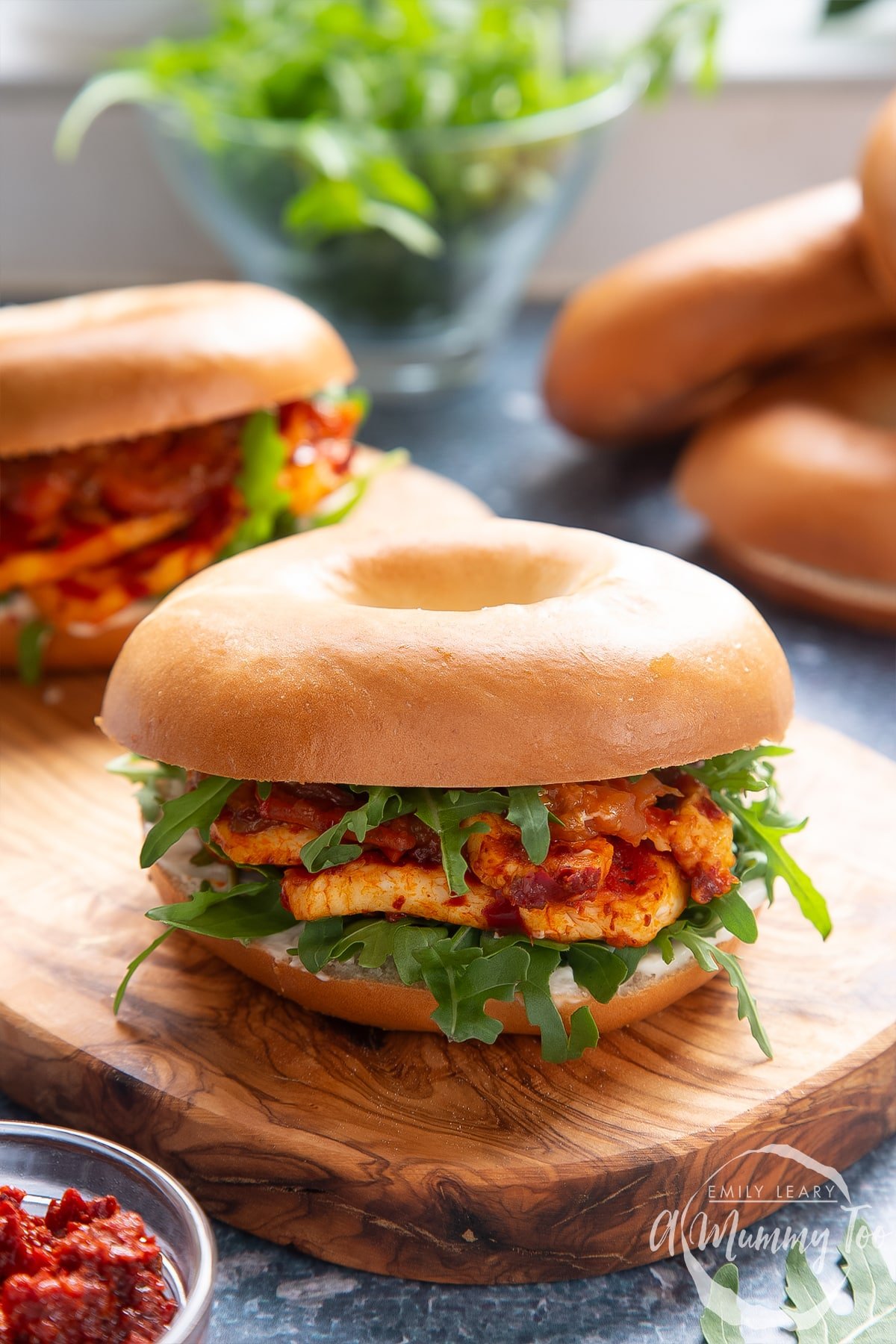 Two halloumi bagels on a wooden board.