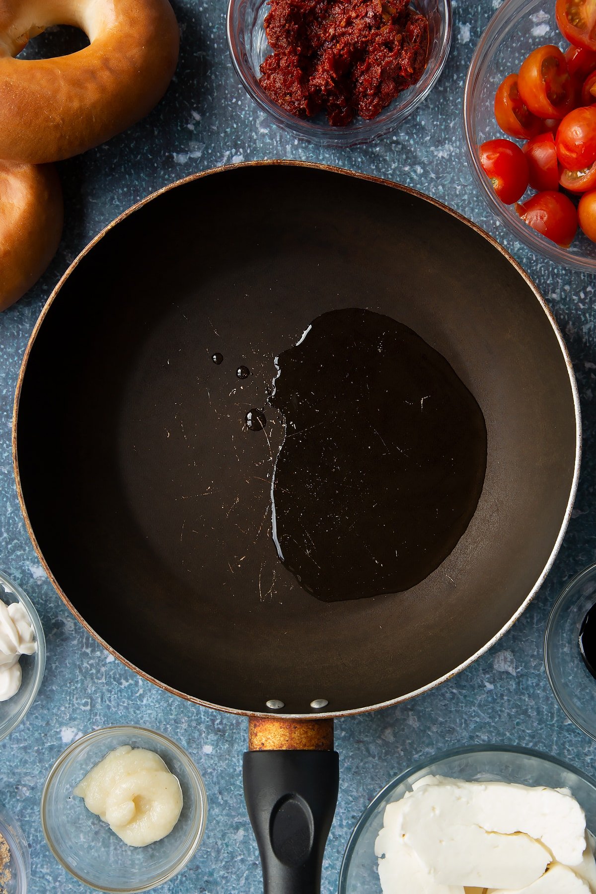 Oil in a frying pan. Ingredients to make halloumi bagels surround the pan.