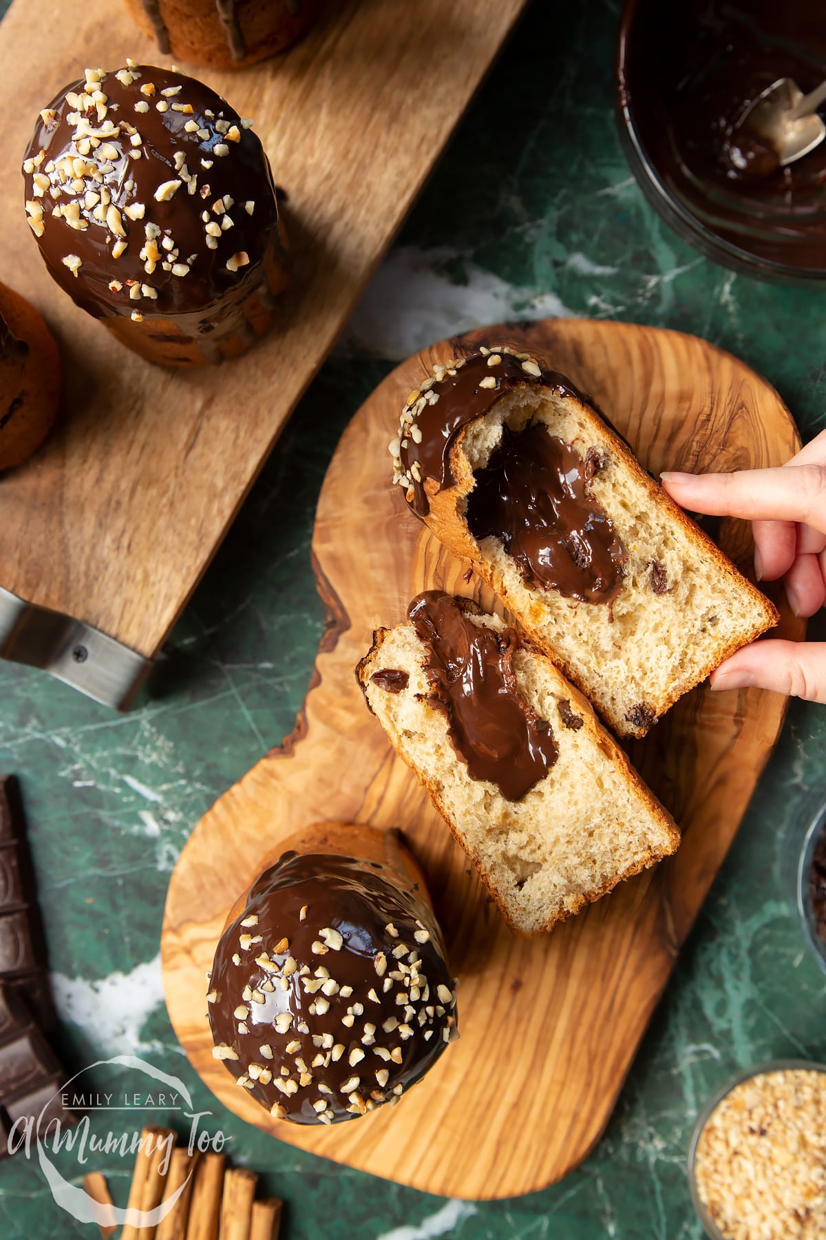 Nutella panettone standing on wooden boards. One of the panettone has been torn in half. A hand reaches for it.