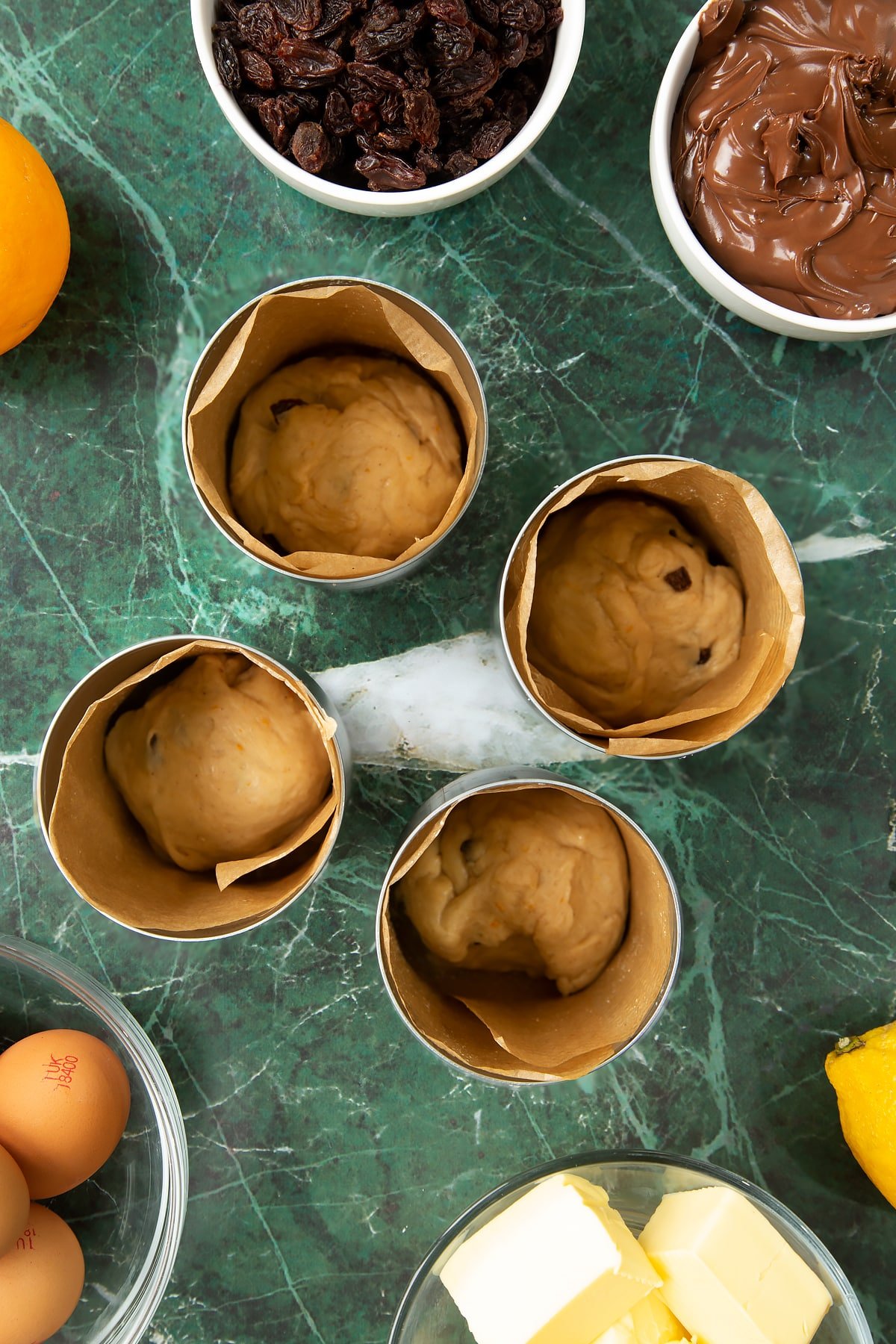 4 lined tin cans with a little dough at the bottom of eacch. Ingredients to make Nutella panettone surround the cans.