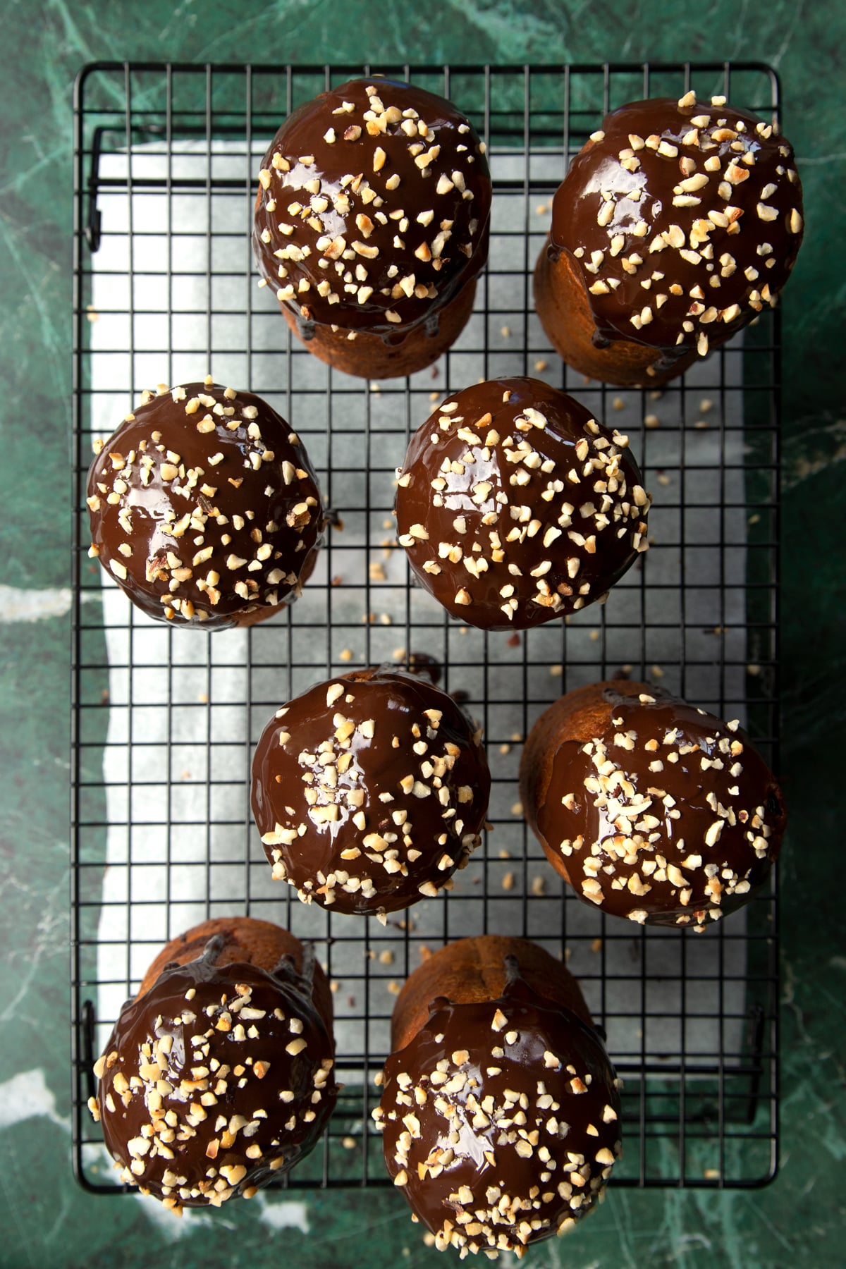 8 cooled Nutella panettone on a wire rack, drizzled with melted chocolate and scattered with chopped hazelnuts.