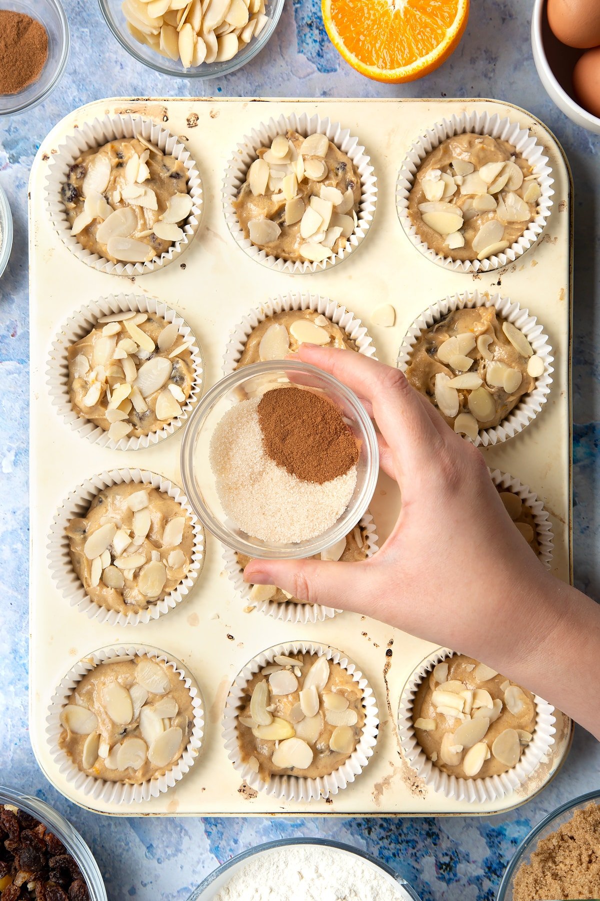 Overhead shot of a hand holding a small clear bowl with cinnamon and sugar mix