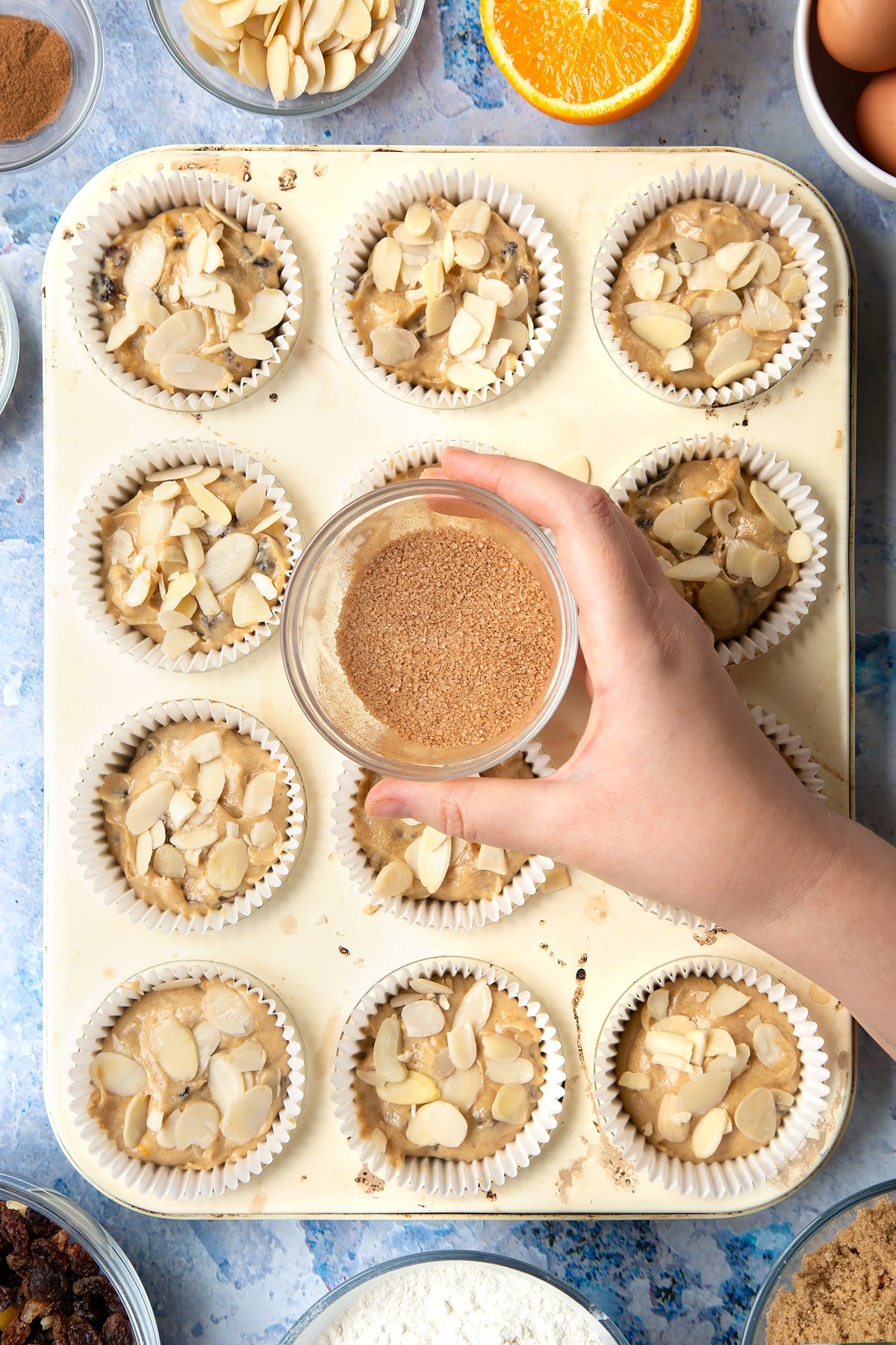 Overhead shot of a hand holding a small clear bowl with cinnamon and sugar mix combined