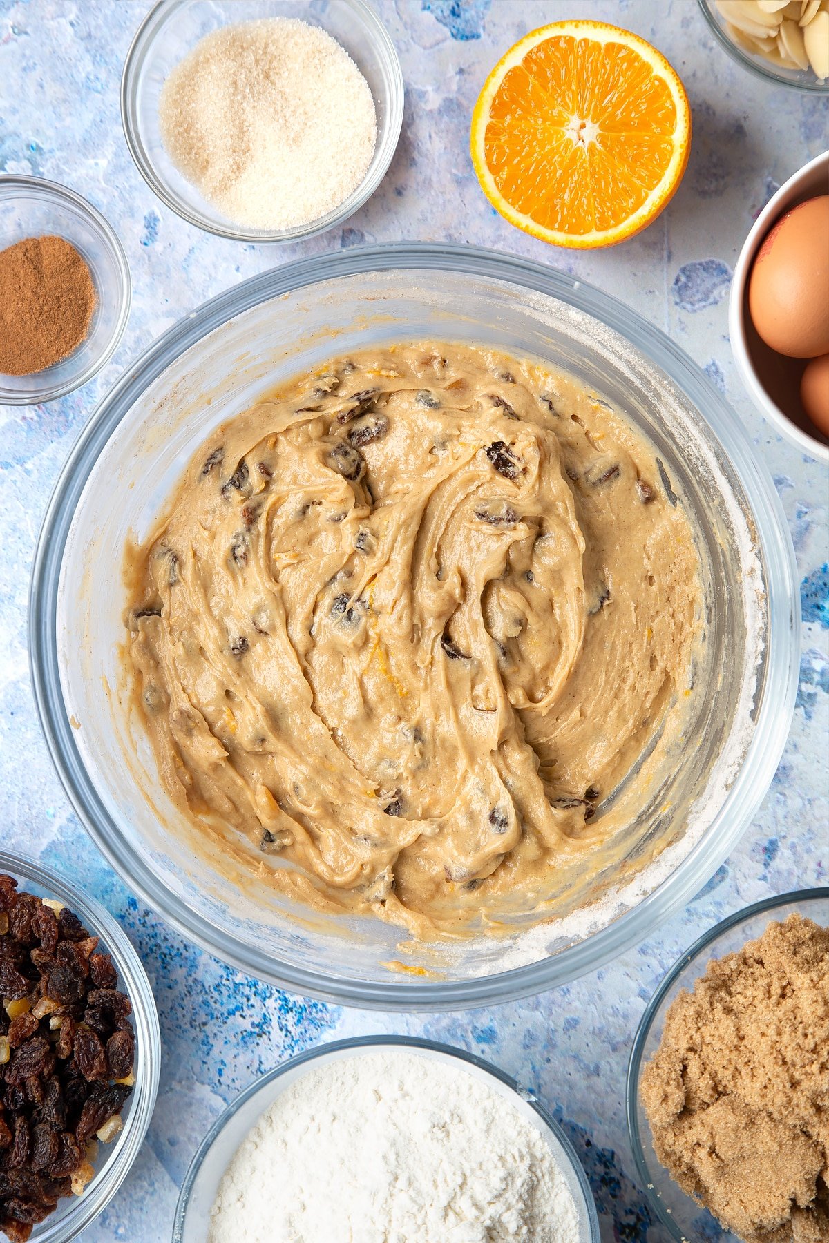 Overhead shot of orange and cinnamon muffin batter in a large clear bowl