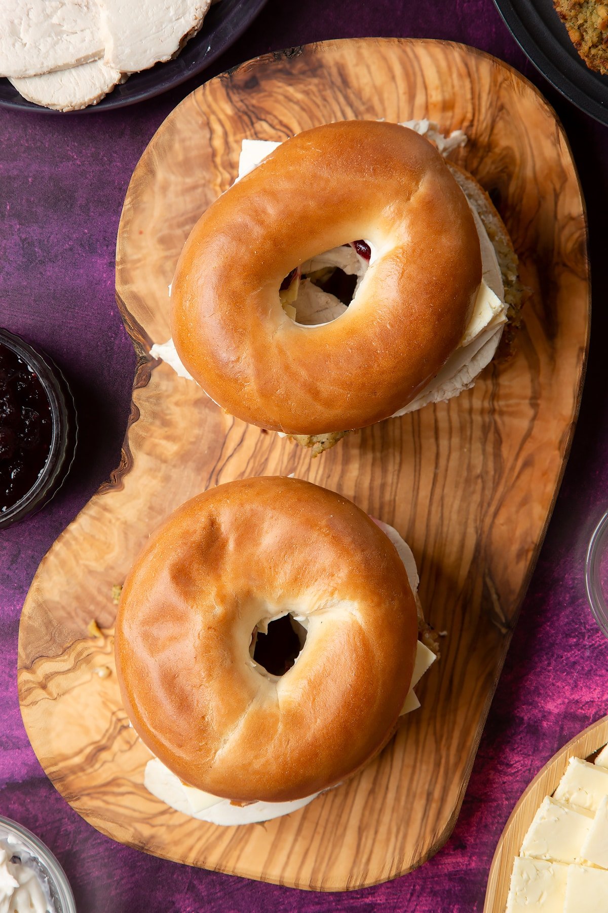 Overhead shot of festive turkey bagel sandwich on a wooden board