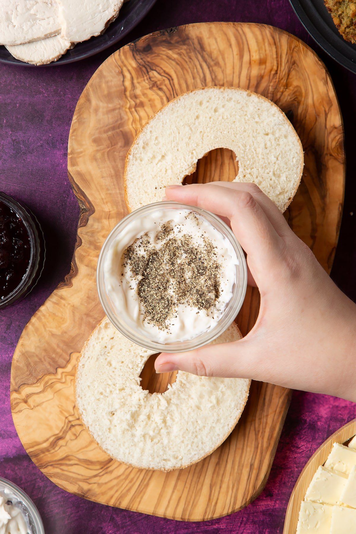 Overhead shot of a hand holding mayo and black pepper in a small bowl