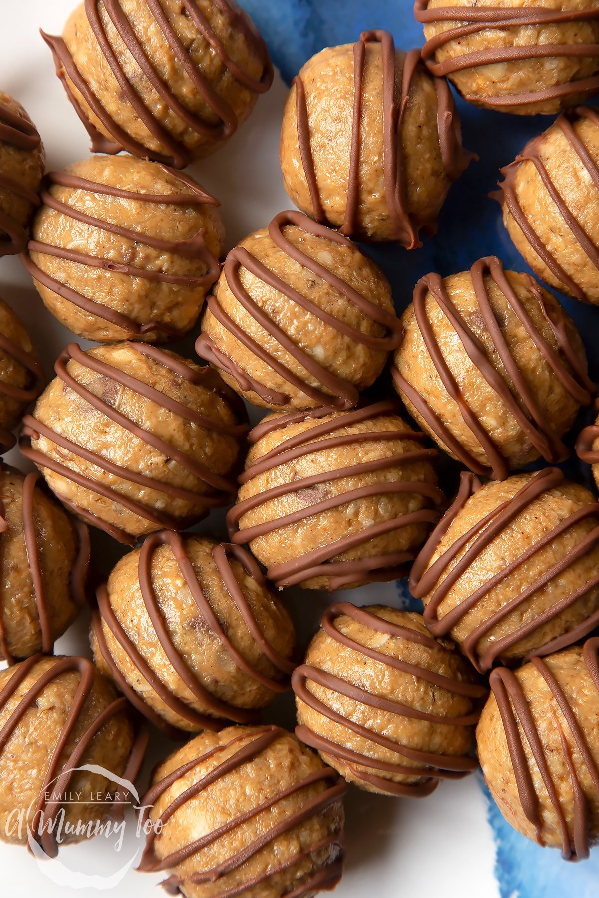 Close up of 3 ingredient peanut butter and oatmeal balls decorated with chocolate on a blue and white plate. 