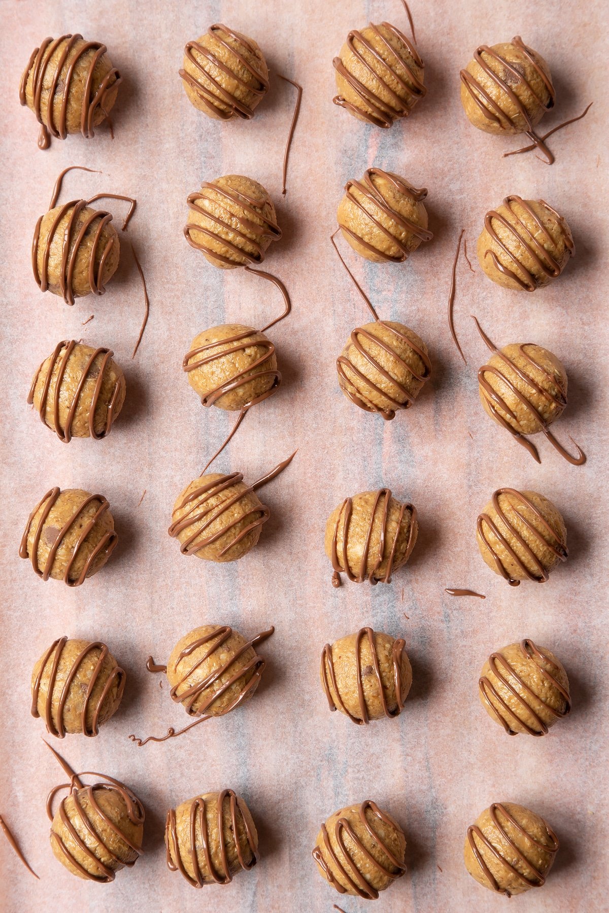 Peanut butter and oatmeal balls decorated with chocolate on a sheet of baking paper.