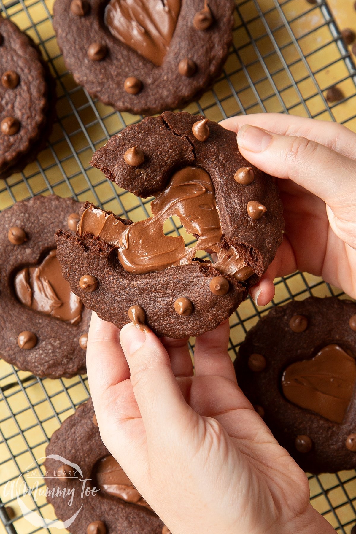 Two hands holding a Nutella sandwich cookie. The cookie is broken in half and being pulled apart.