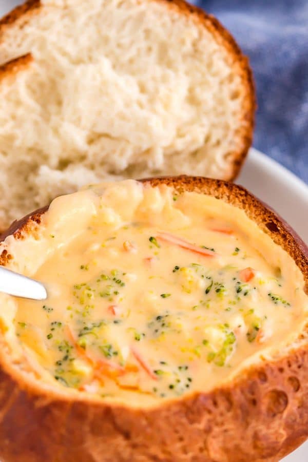 A large bread bowl filled with a Copycat Panera Broccoli Cheese Soup.