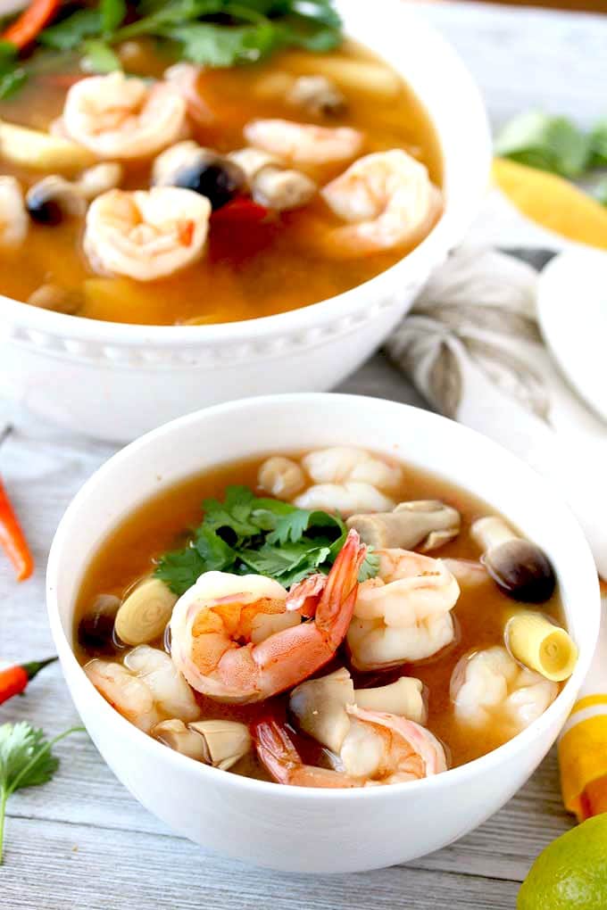 Close up of a white bowl filled with Tom Yum Soup also known as Hot and Sour Soup.