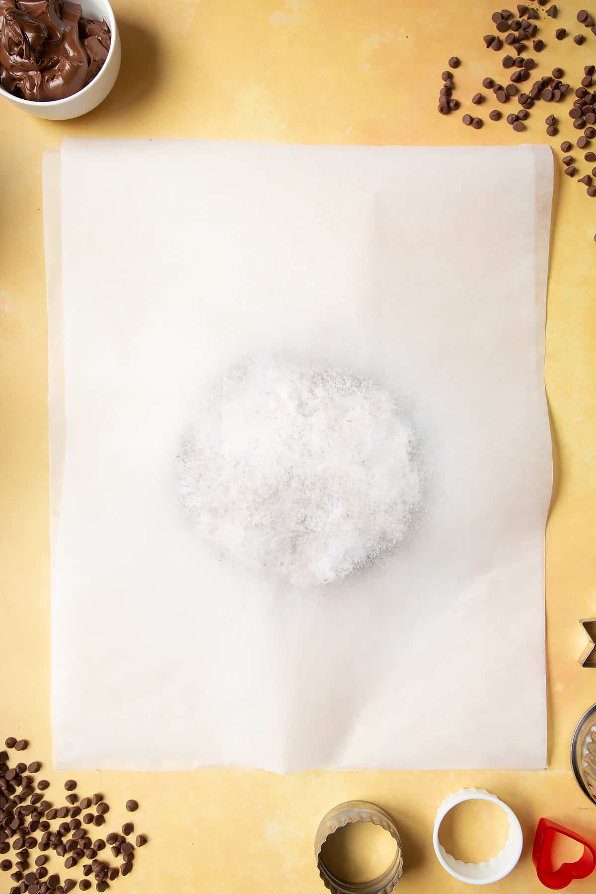 Chocolate shortbread dough dusted with icing sugar and pressed between two pieces of baking paper. 