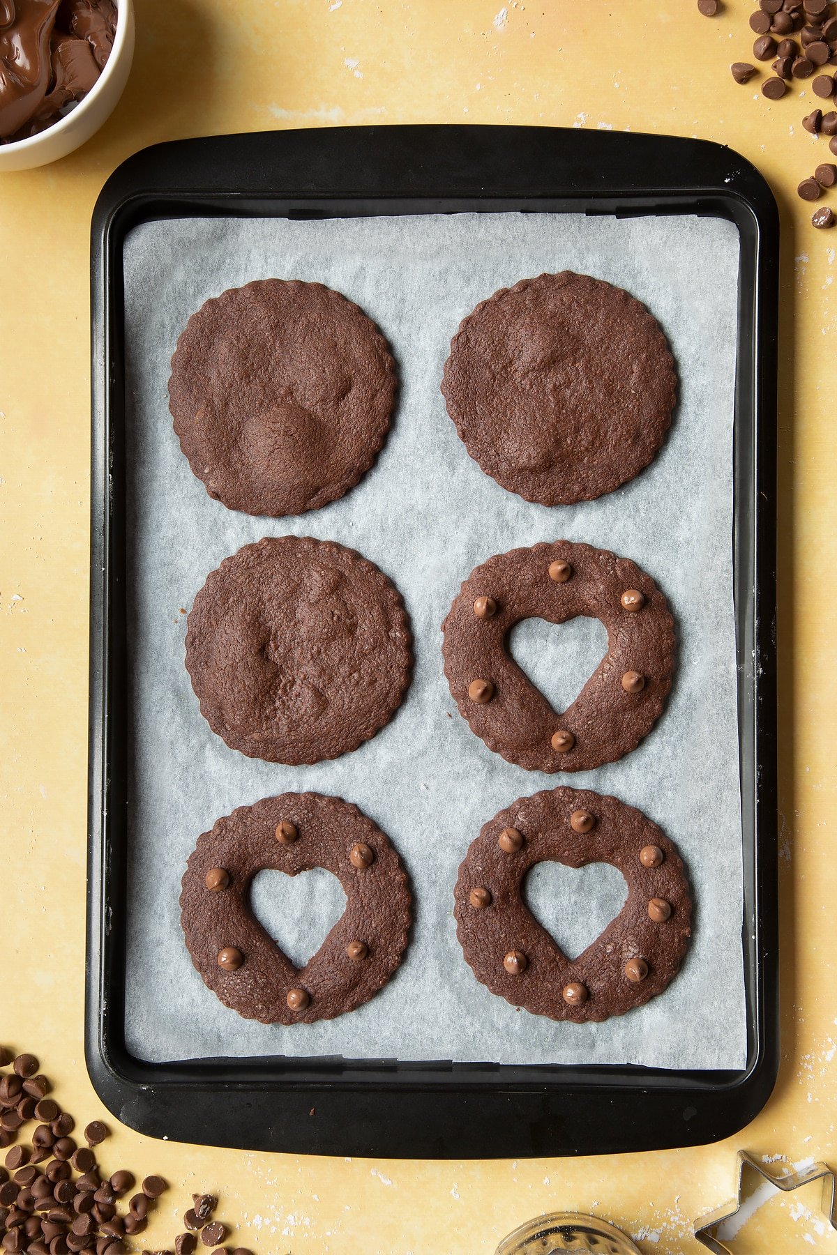 Freshly baked chocolate sandwich cookies on a tray lined with baking paper.