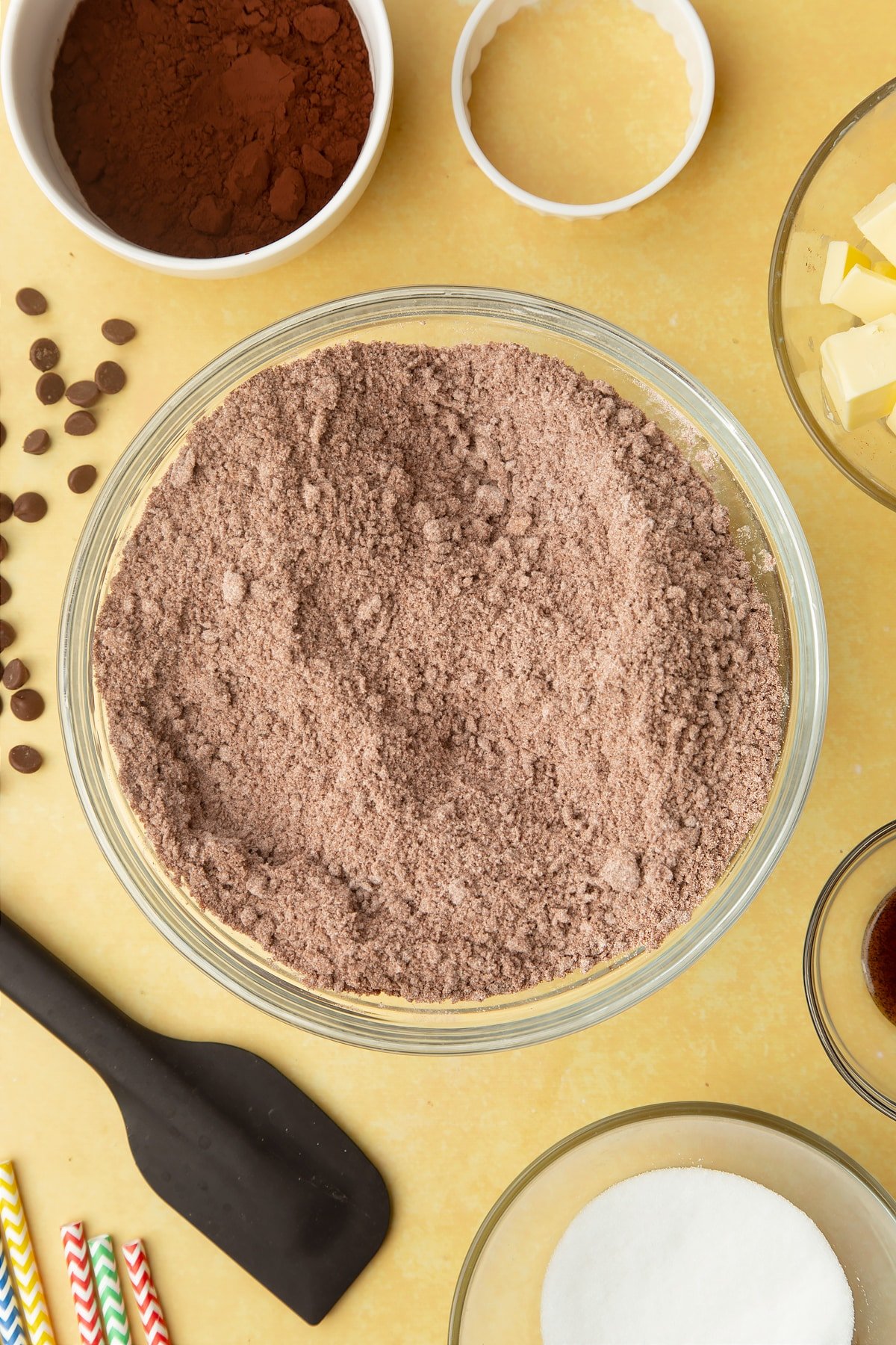 Cocoa, sugar, flour and butter rubbed together. Ingredients to make Nutella sandwich cookies surround the bowl.