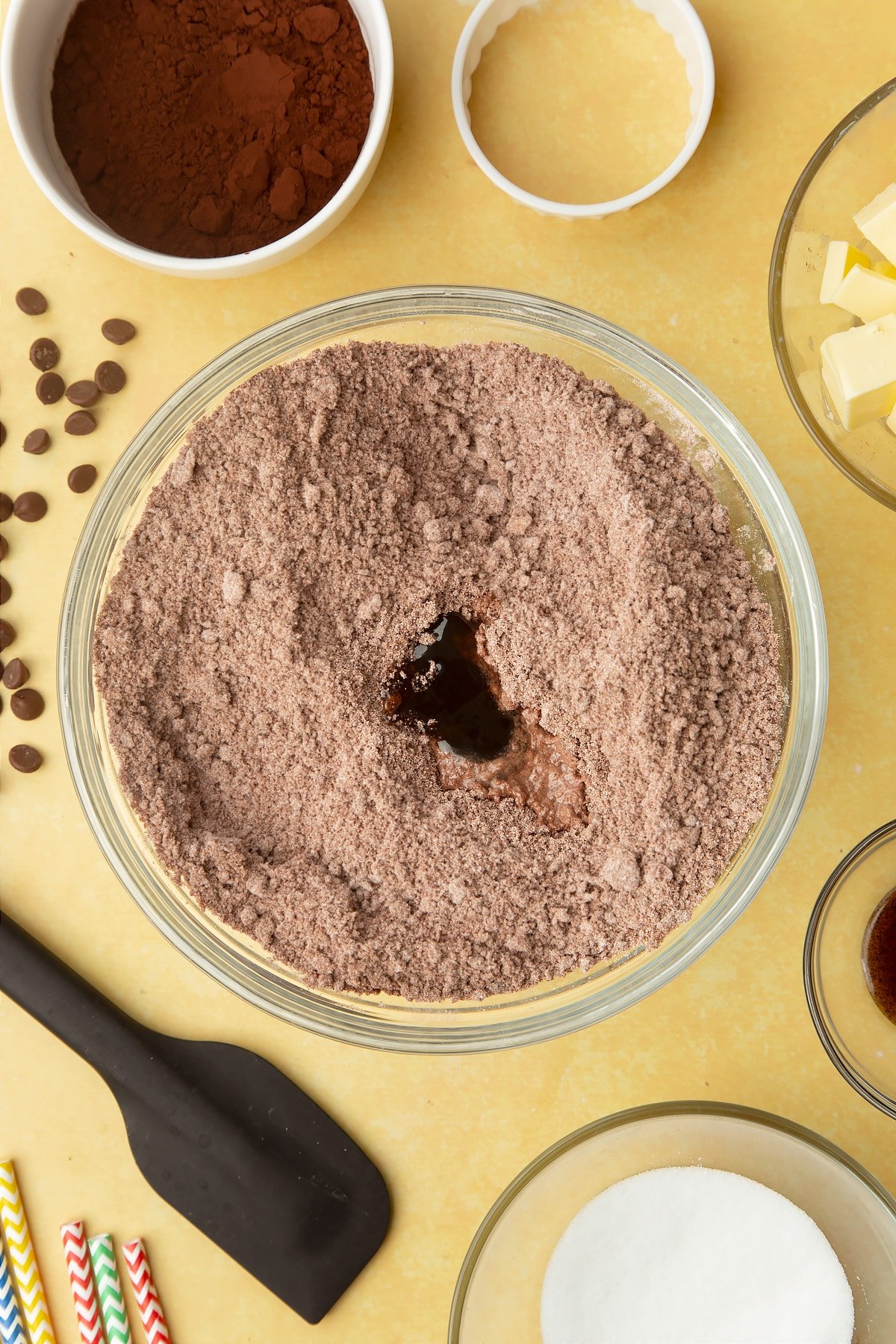 Cocoa, sugar, flour and butter rubbed together. A little vanilla and water sits on top. Ingredients to make Nutella sandwich cookies surround the bowl.