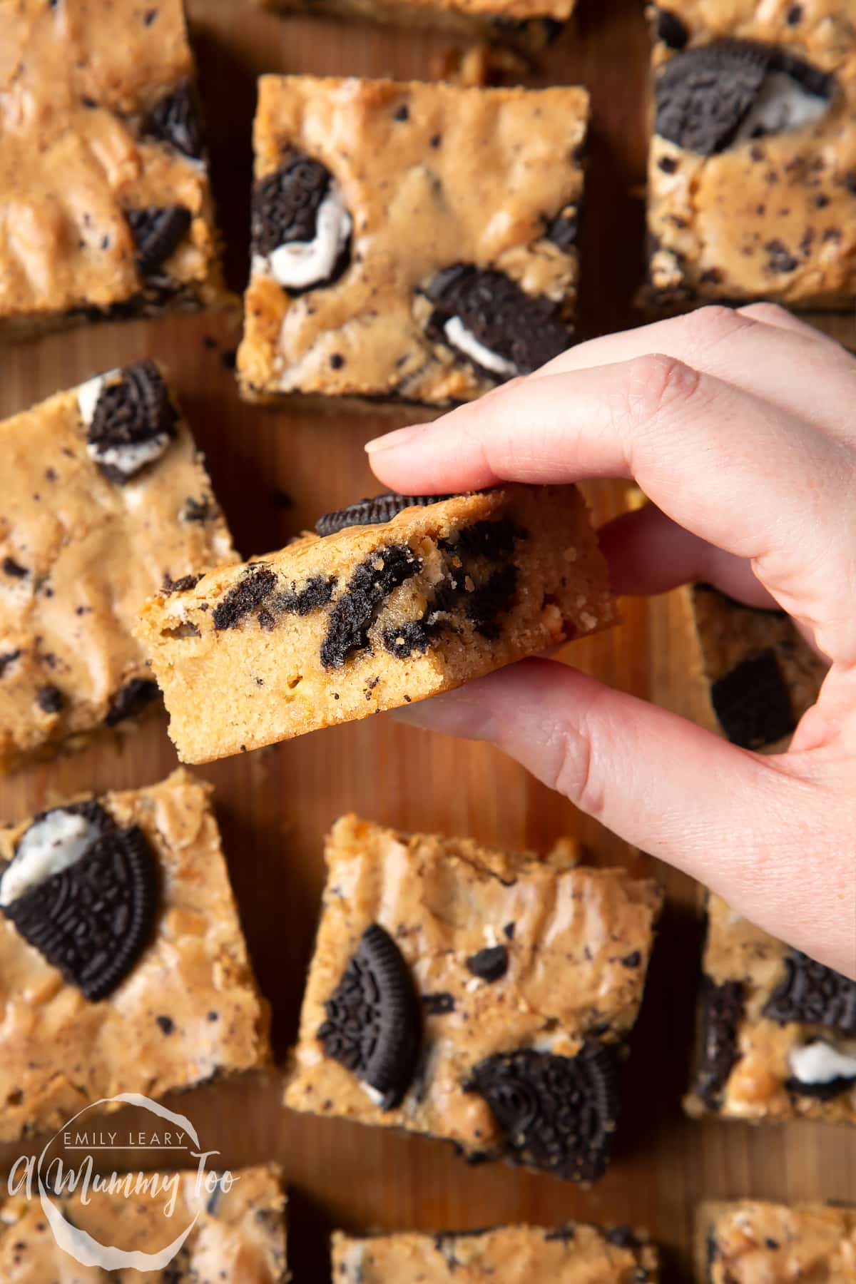 Overhead view of a hand holding an Oreo Blondie over a wooden board