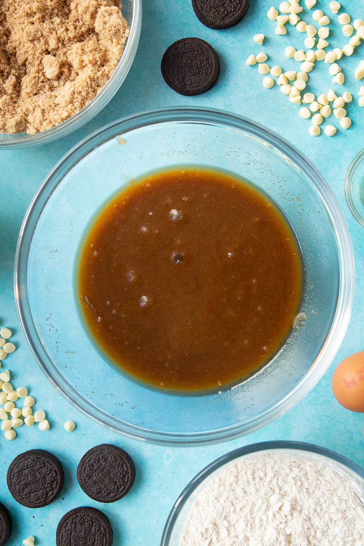 Overhead shot of melted butter and brown sugar mixed in a large clear bowl