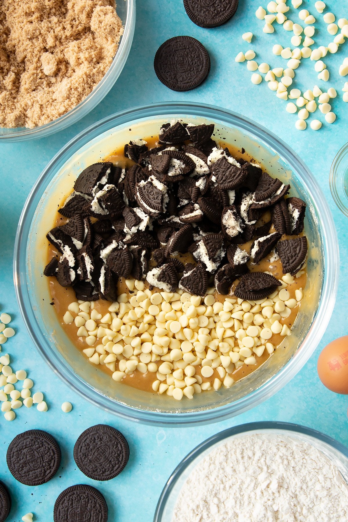 Overhead shot of blondies mix with chopped Oreo cookies in a large clear bowl